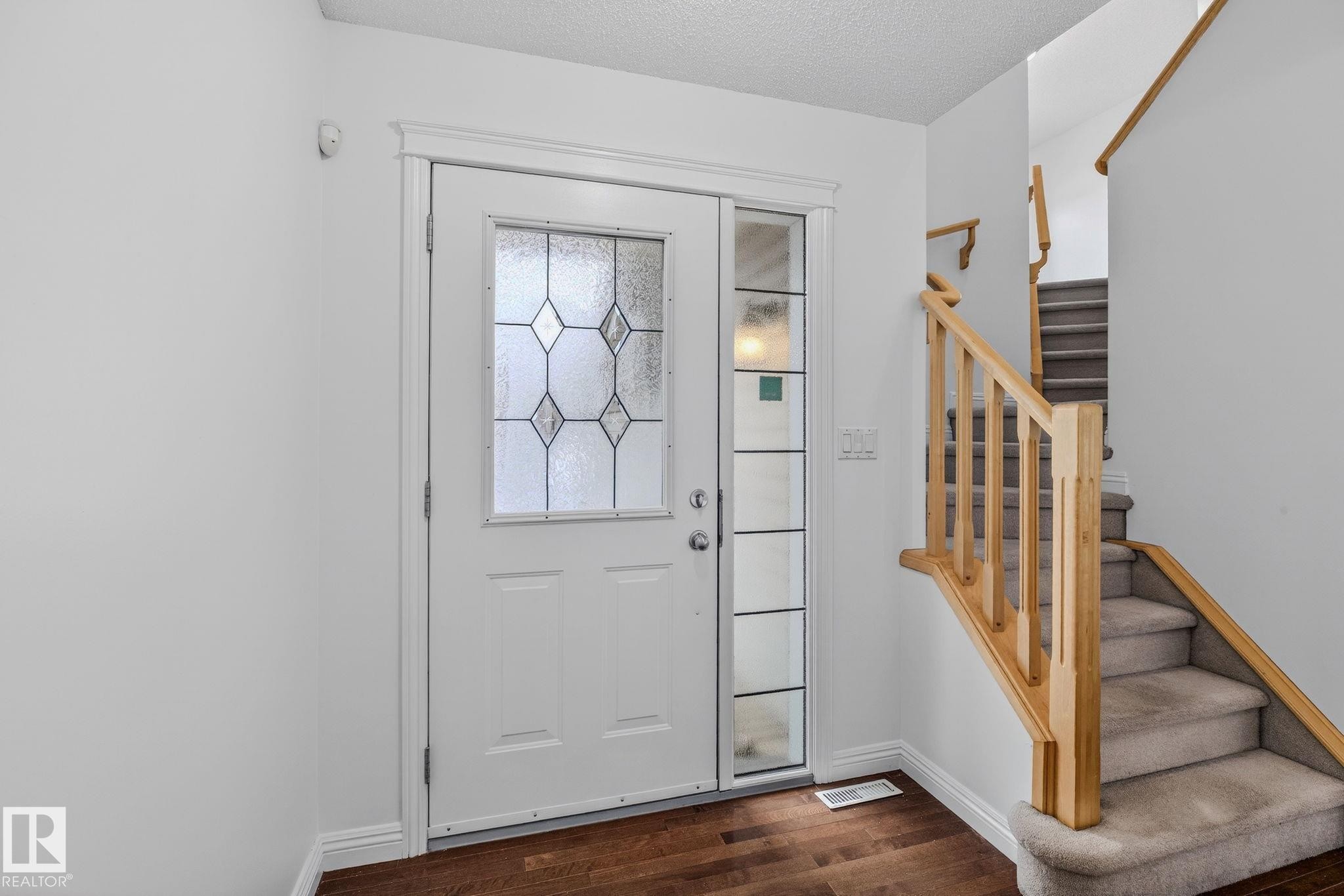 Entryway featuring a white door with decorative glass, a coordinating sidelight, and dark wood-finish flooring - 978 Rutherford Road Sw, Edmonton, AB - Indoor Photo Showing Other Room