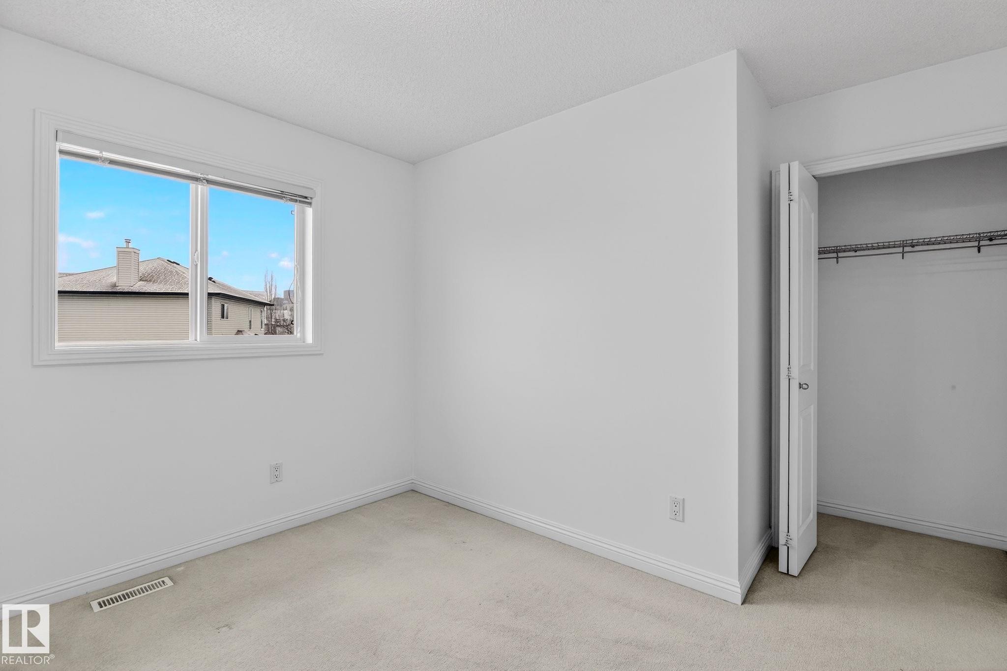 Carpeted room featuring a white trim window, neutral wall paint, and a built-in closet with an organizational rod - 978 Rutherford Road Sw, Edmonton, AB - Indoor Photo Showing Other Room