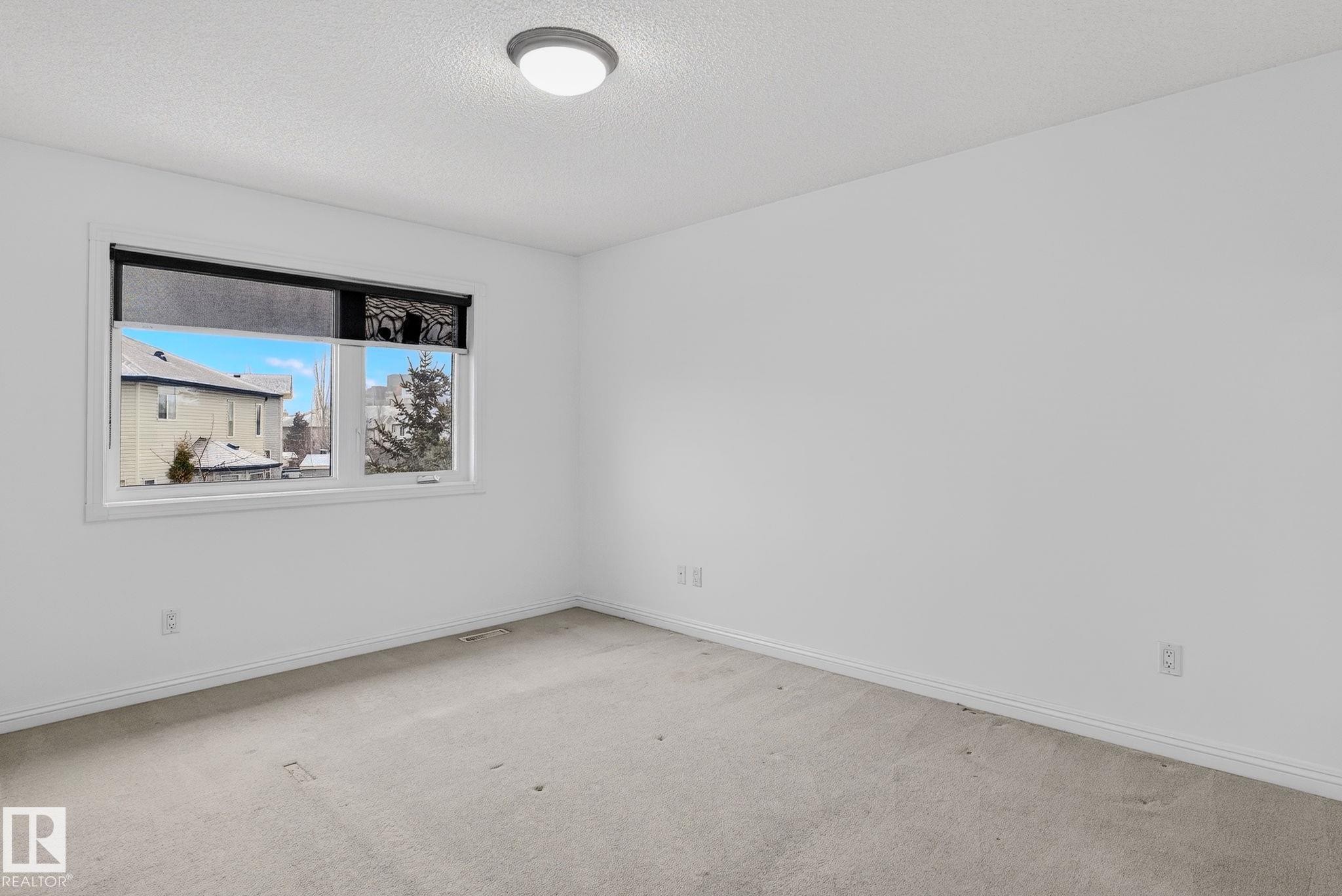 Neutral-toned room with light-colored carpeting, white baseboards, and a flush-mount ceiling light fixture - 978 Rutherford Road Sw, Edmonton, AB - Indoor Photo Showing Other Room