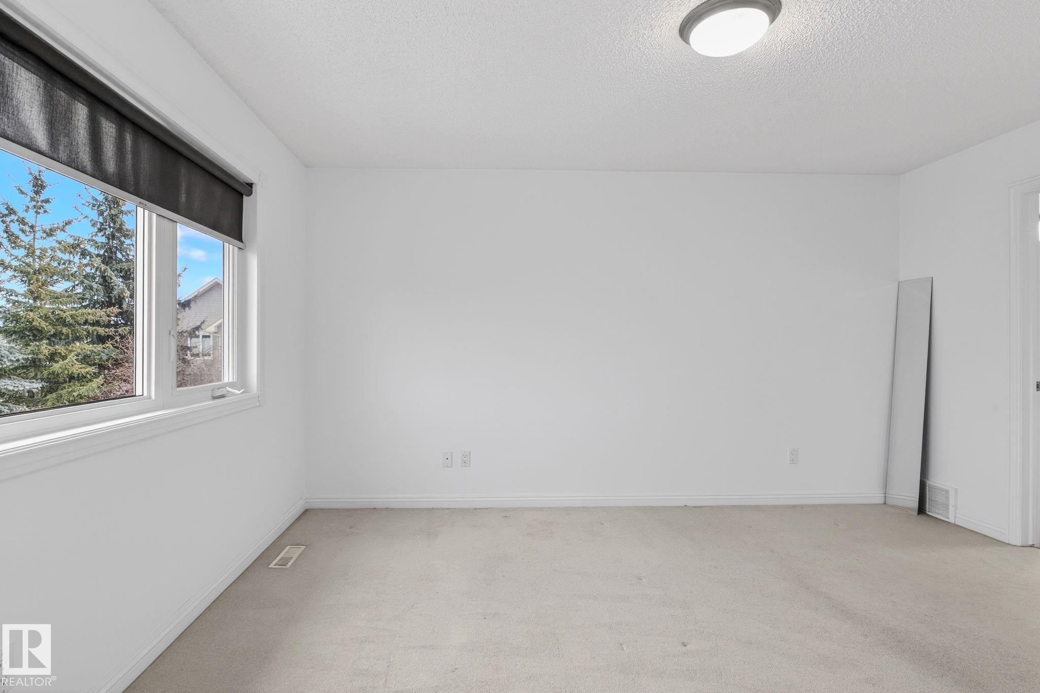 Bright room featuring white walls, carpet flooring, a multi-pane window, and a flush-mount ceiling light fixture - 978 Rutherford Road Sw, Edmonton, AB - Indoor Photo Showing Other Room