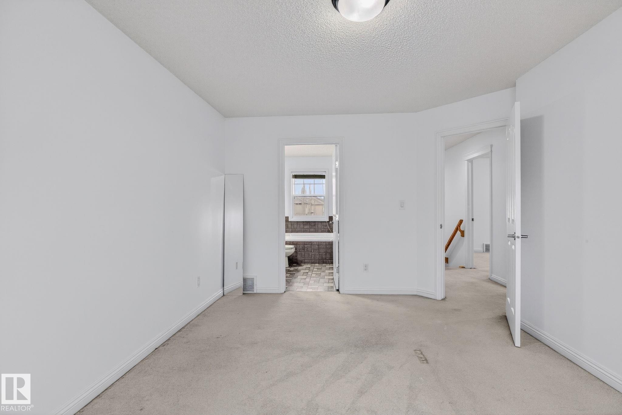 Interior space featuring neutral carpeting, white walls, and a textured ceiling with a flush-mount light fixture - 978 Rutherford Road Sw, Edmonton, AB - Indoor Photo Showing Other Room