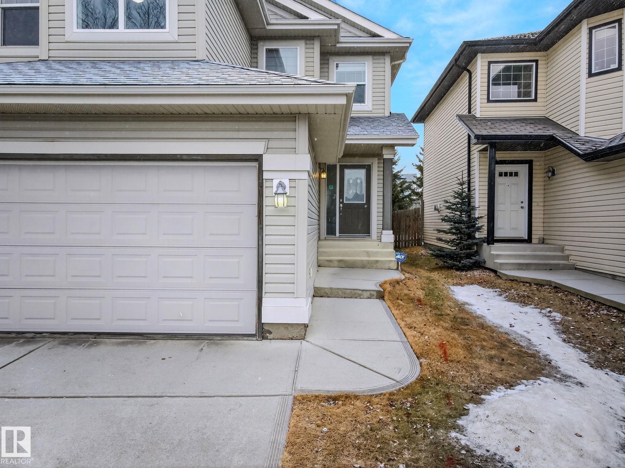 Attached single-car garage featuring a panel-style door and an exterior wall lantern - 978 Rutherford Road Sw, Edmonton, AB - Outdoor