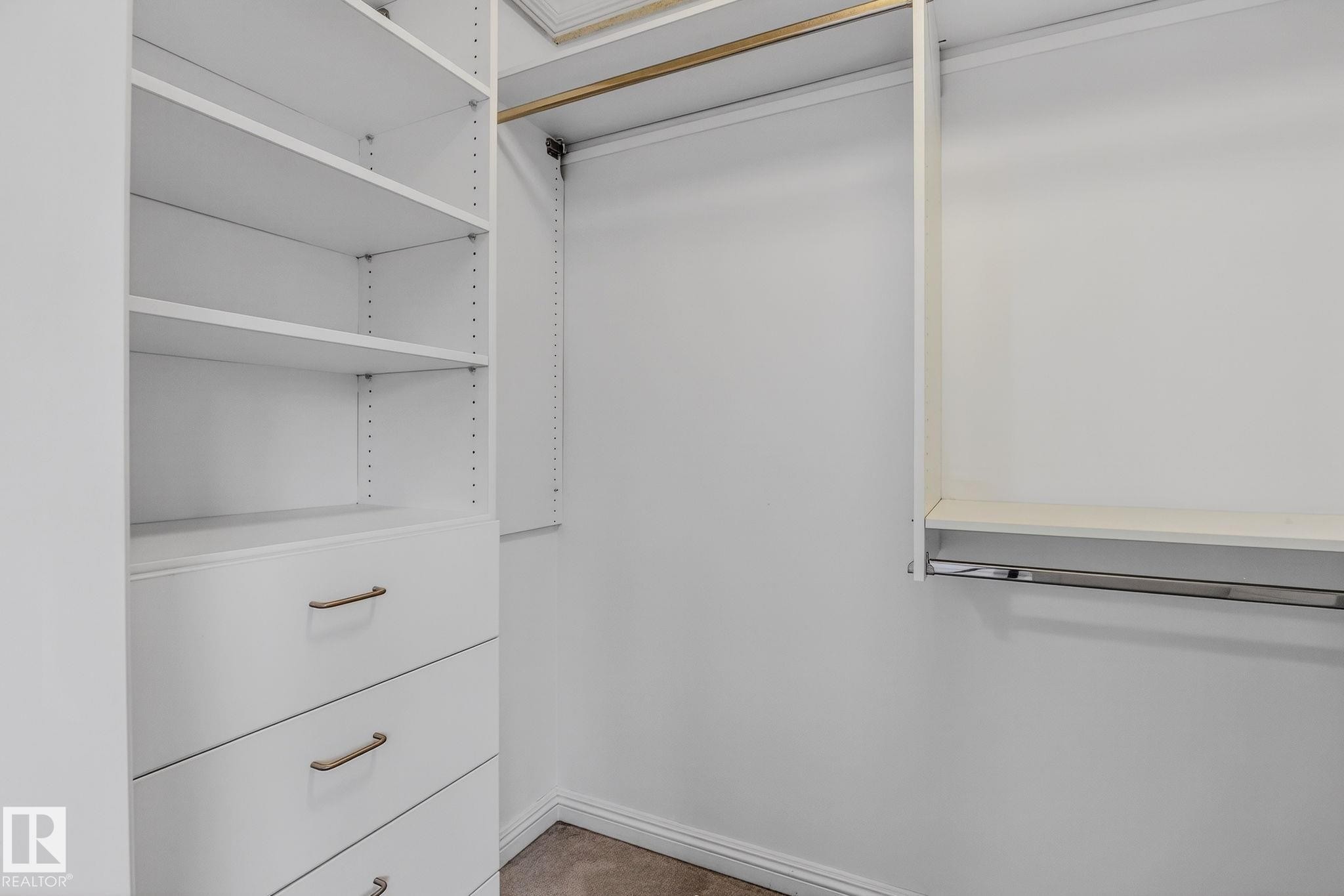 Custom closet organization system featuring multiple adjustable shelves, integrated drawers with brushed nickel hardware, and dual hanging rods - 978 Rutherford Road Sw, Edmonton, AB - Indoor With Storage