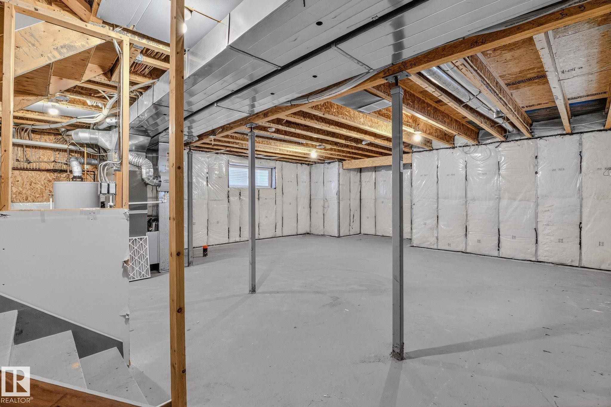 Spacious unfinished basement featuring exposed wood joists, bright overhead lighting, and insulated perimeter walls - 978 Rutherford Road Sw, Edmonton, AB - Indoor Photo Showing Basement