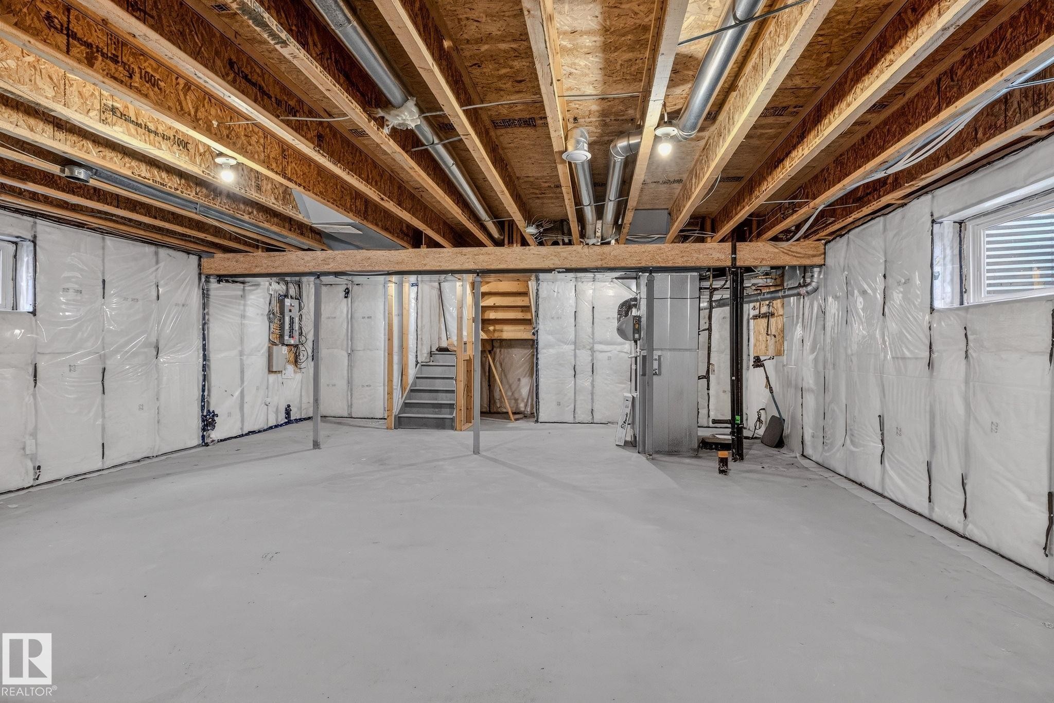Expansive open lower level featuring a concrete floor, exposed wood ceiling joists, and visible utility systems - 978 Rutherford Road Sw, Edmonton, AB - Indoor Photo Showing Basement