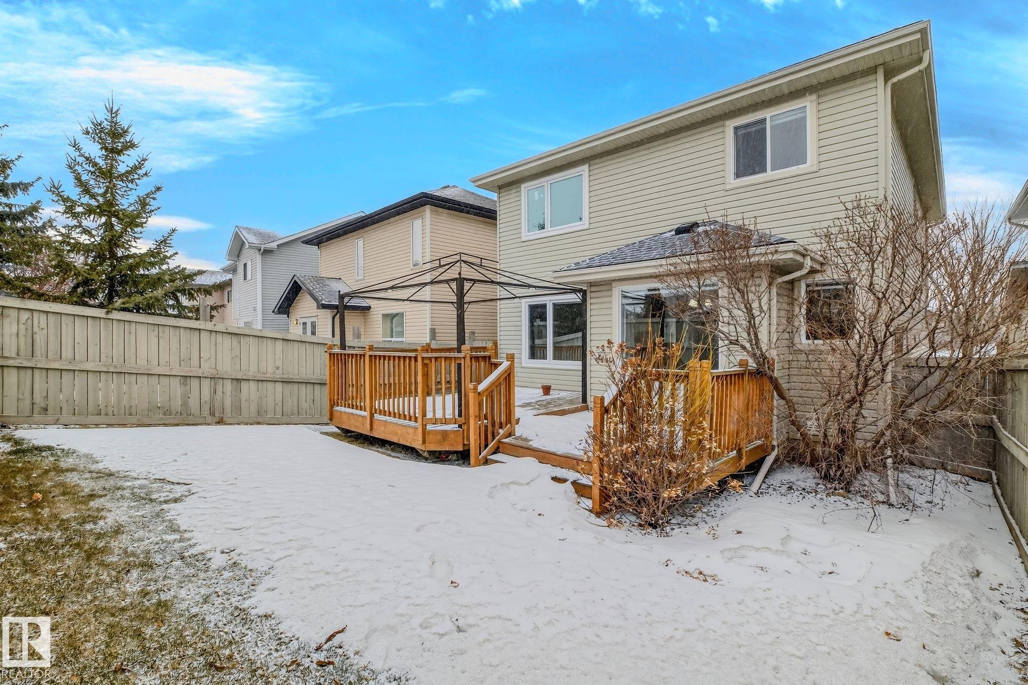Rear exterior featuring a multi-level wood deck, light-colored siding, and a fenced perimeter - 978 Rutherford Road Sw, Edmonton, AB - Outdoor
