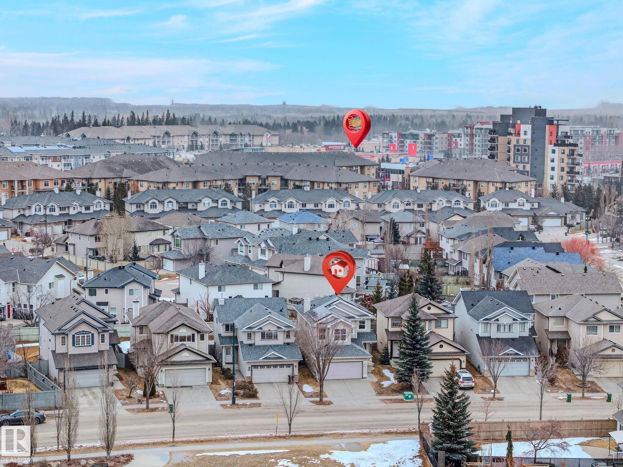 Residential neighborhood featuring detached homes with attached garages, multi-story apartment buildings, and distant tree lines - 978 Rutherford Road Sw, Edmonton, AB - Outdoor With View