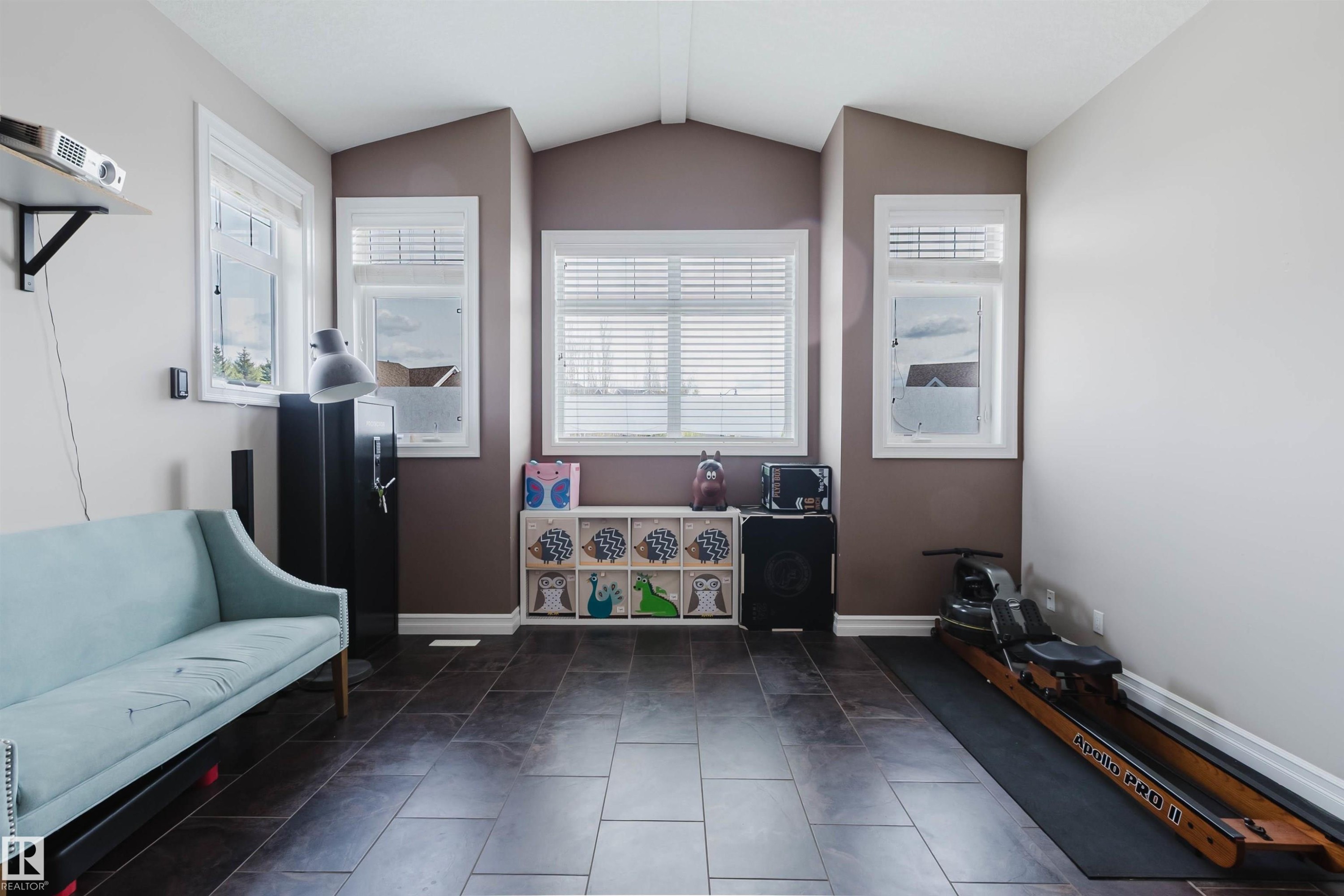 Spacious room featuring dark rectangular floor tiles, multiple windows with white blinds, and crisp white baseboards - 3412 Macneil Link, Edmonton, AB - Indoor