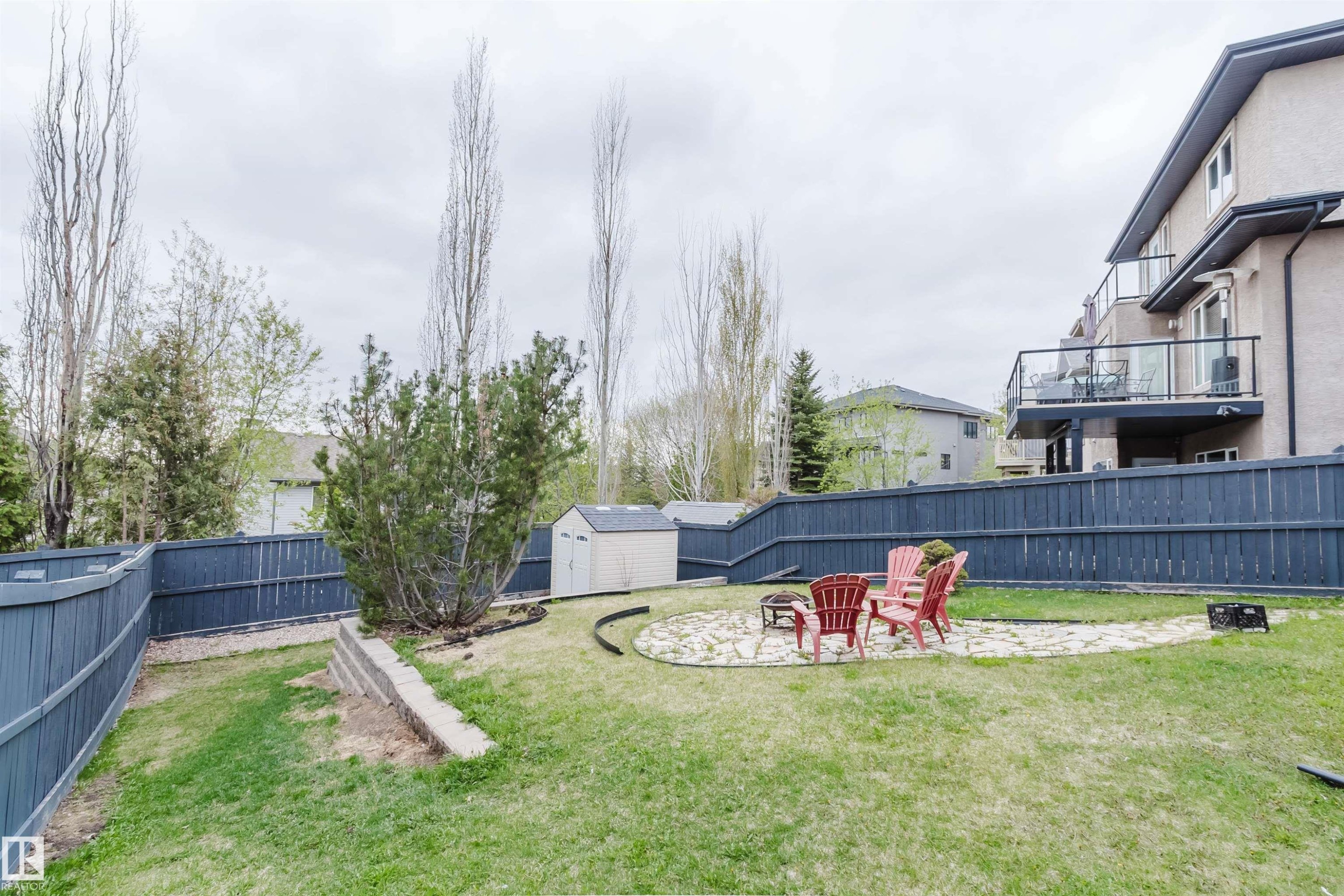 Expansive backyard featuring a stone patio area with a fire pit, a storage shed, and mature perimeter fencing - 3412 Macneil Link, Edmonton, AB - Outdoor