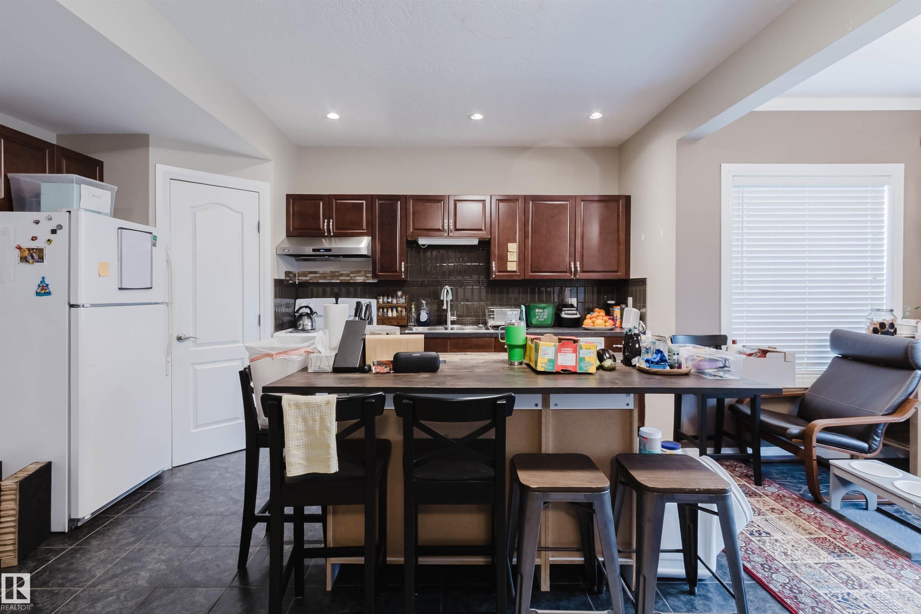 Kitchen featuring dark wood cabinetry, a dark tile backsplash, and recessed lighting - 3412 Macneil Link, Edmonton, AB - Indoor