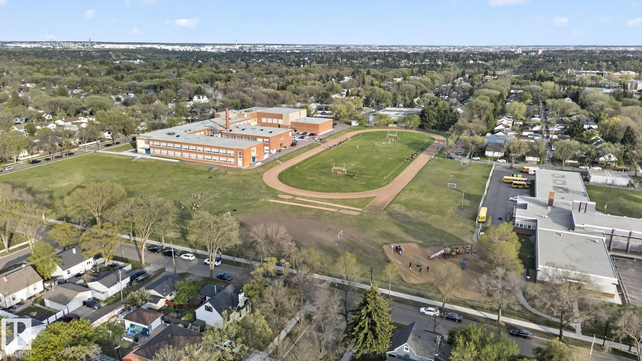 Aerial perspective showcasing a sprawling educational campus with multiple buildings, athletic fields, and a running track - 11614 70 Street, Edmonton, AB