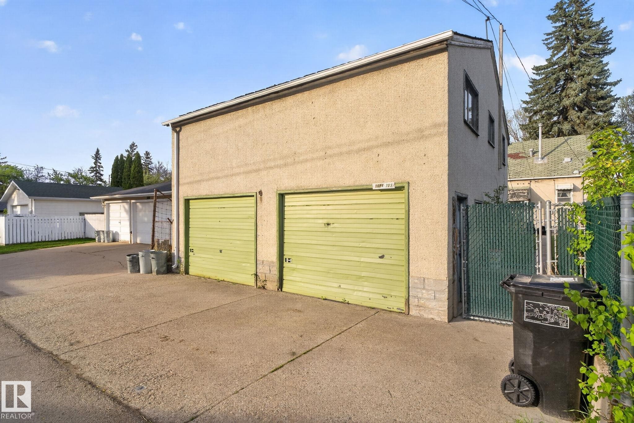 Detached two-story garage with two roll-up doors, stucco exterior, and a concrete driveway - 11614 70 Street, Edmonton, AB