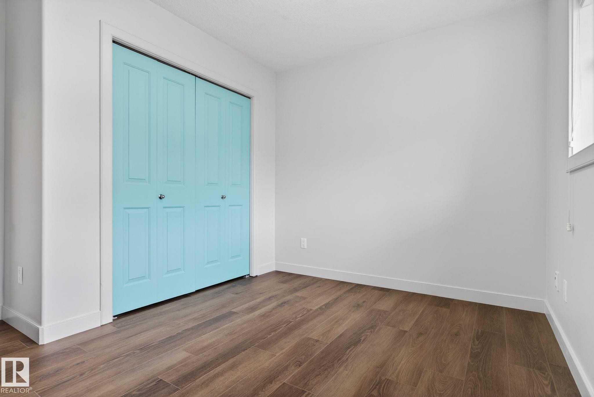 Room featuring wood-finish flooring, crisp white walls, and a window providing natural light - 11 450 Mcconachie Way, Edmonton, AB - Indoor Photo Showing Other Room