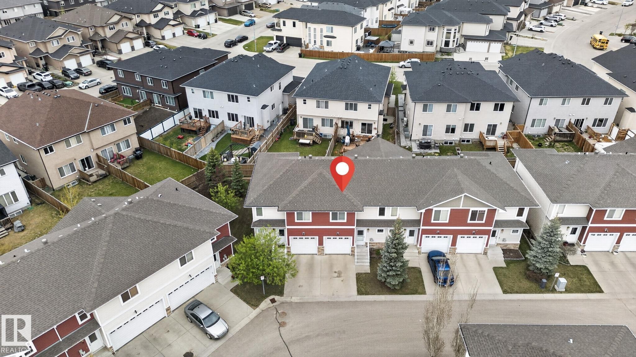 End-unit townhome featuring a red facade and a single-car garage - 11 450 Mcconachie Way, Edmonton, AB - Outdoor