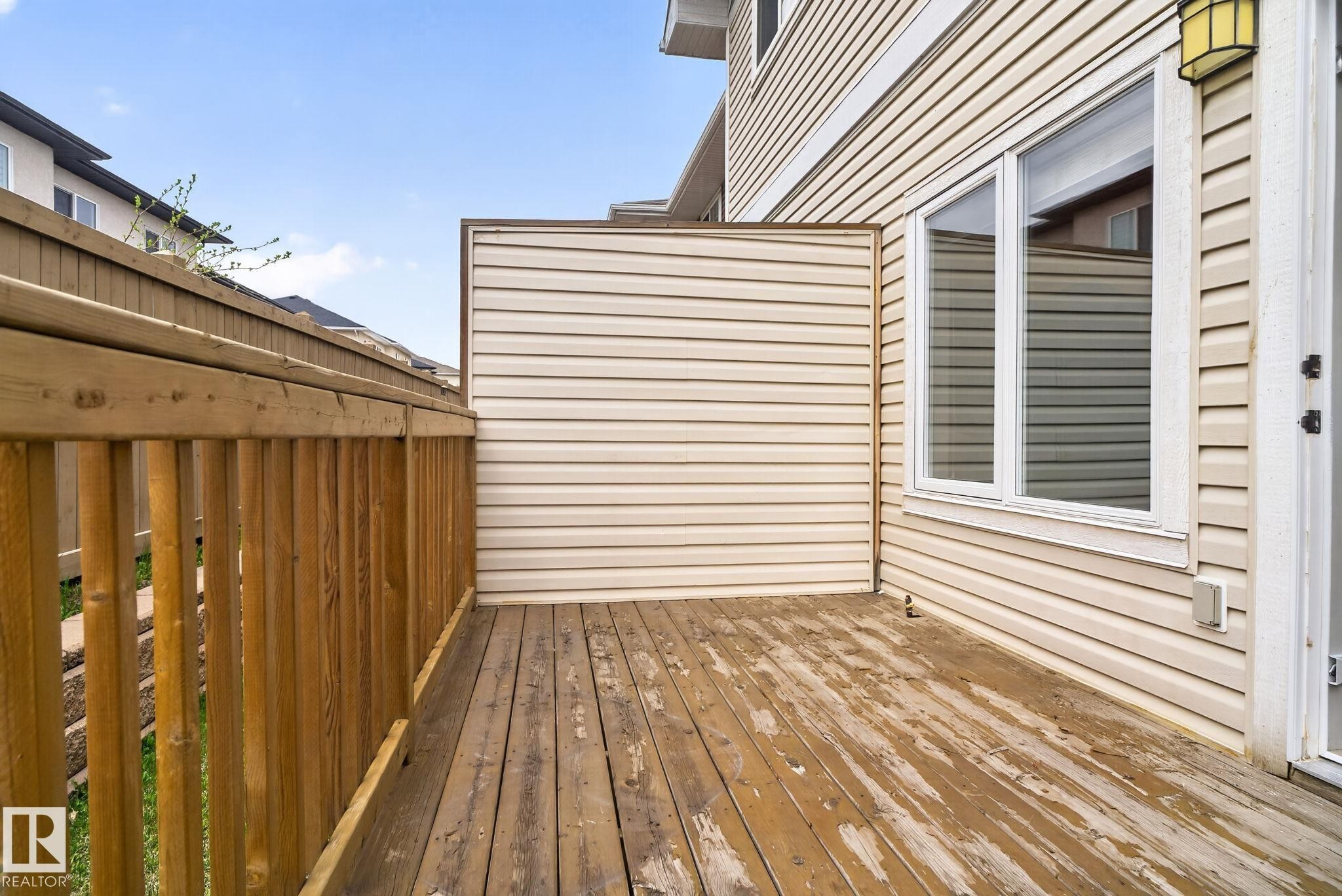 Wood-finish deck with a privacy fence and siding exterior - 11 450 Mcconachie Way, Edmonton, AB - Outdoor With Exterior