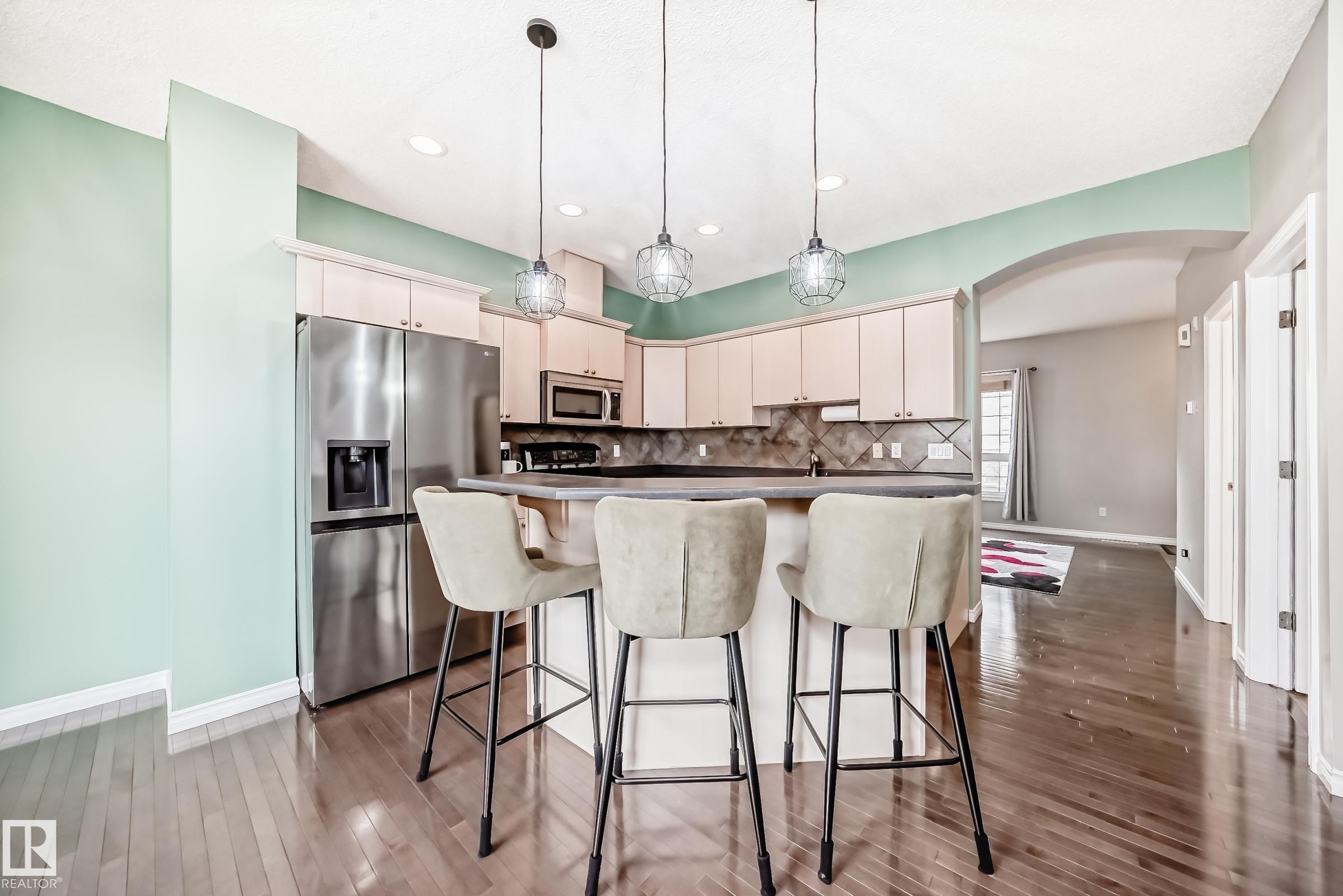 Kitchen with light wood-finish cabinetry, stainless steel appliances, dark countertops, and a patterned tile backsplash - 105 13825 155 Avenue, Edmonton, AB - Indoor Photo Showing Kitchen With Upgraded Kitchen