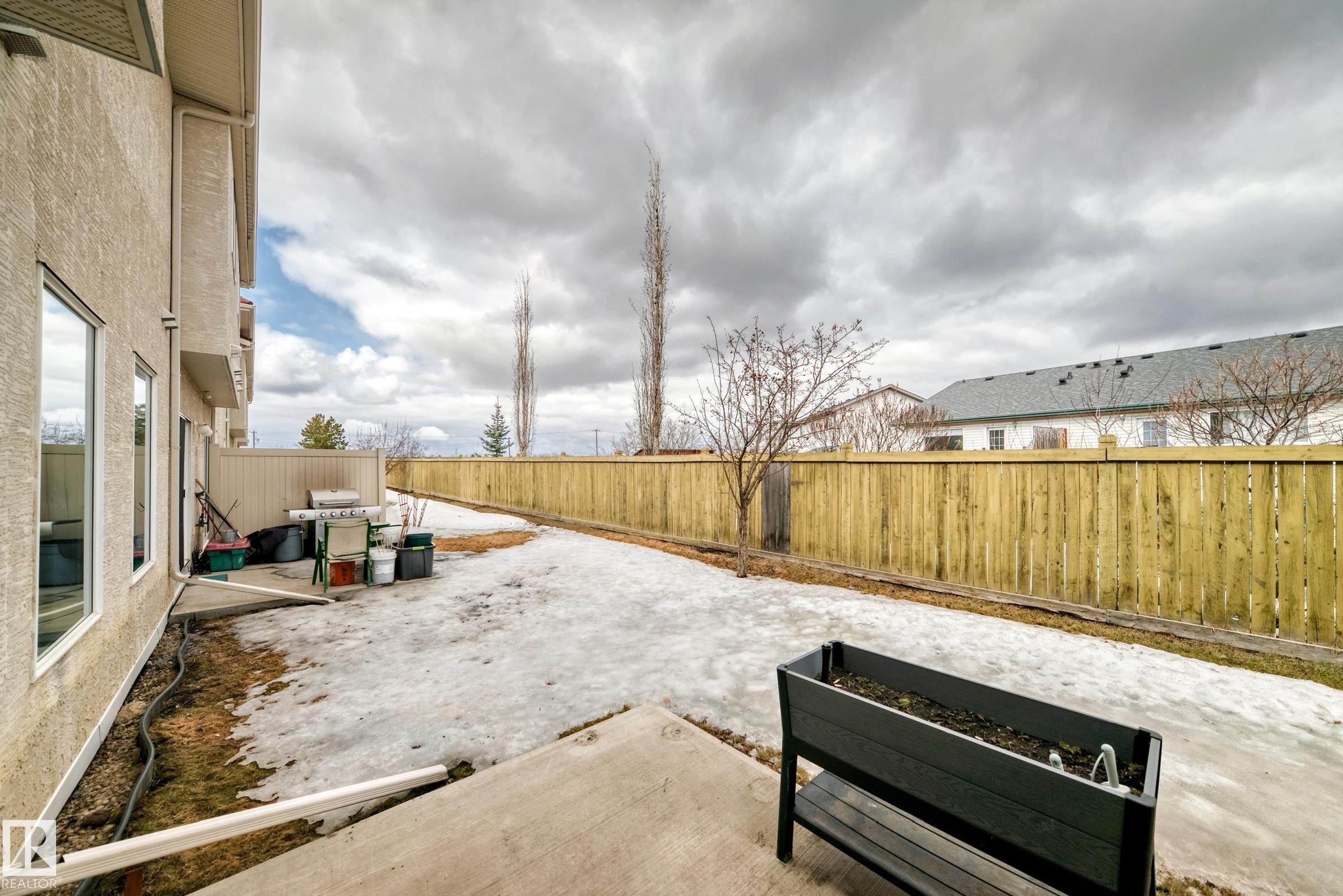 Expansive backyard featuring a new wood privacy fence and concrete patio - 105 13825 155 Avenue, Edmonton, AB - Outdoor