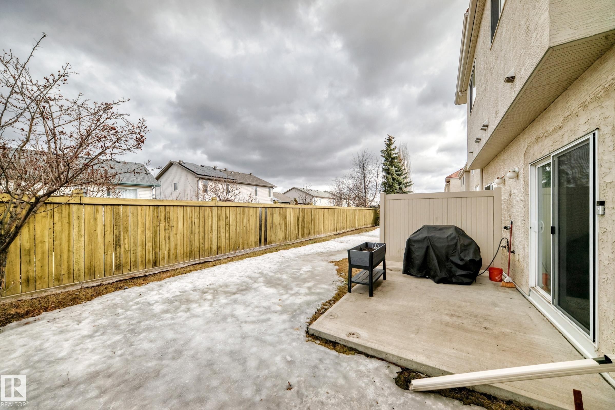 Private outdoor patio space featuring a sliding glass door entry, stucco exterior, and a privacy fence - 105 13825 155 Avenue, Edmonton, AB - Outdoor