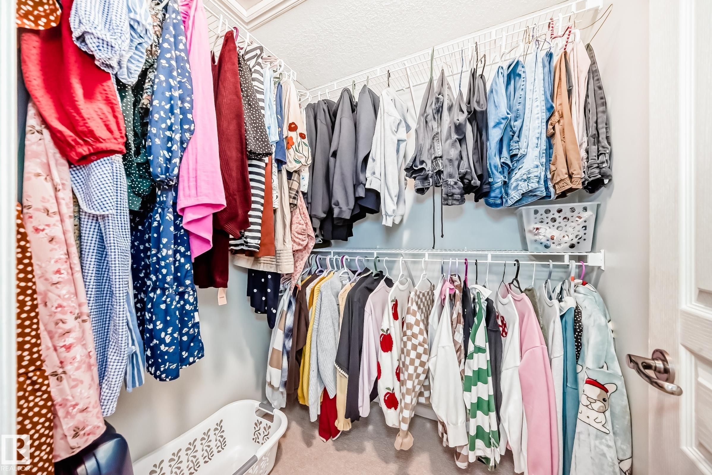 Walk-in closet featuring built-in wire shelving, multiple hanging rods, and light-colored walls - 105 13825 155 Avenue, Edmonton, AB - Indoor With Storage