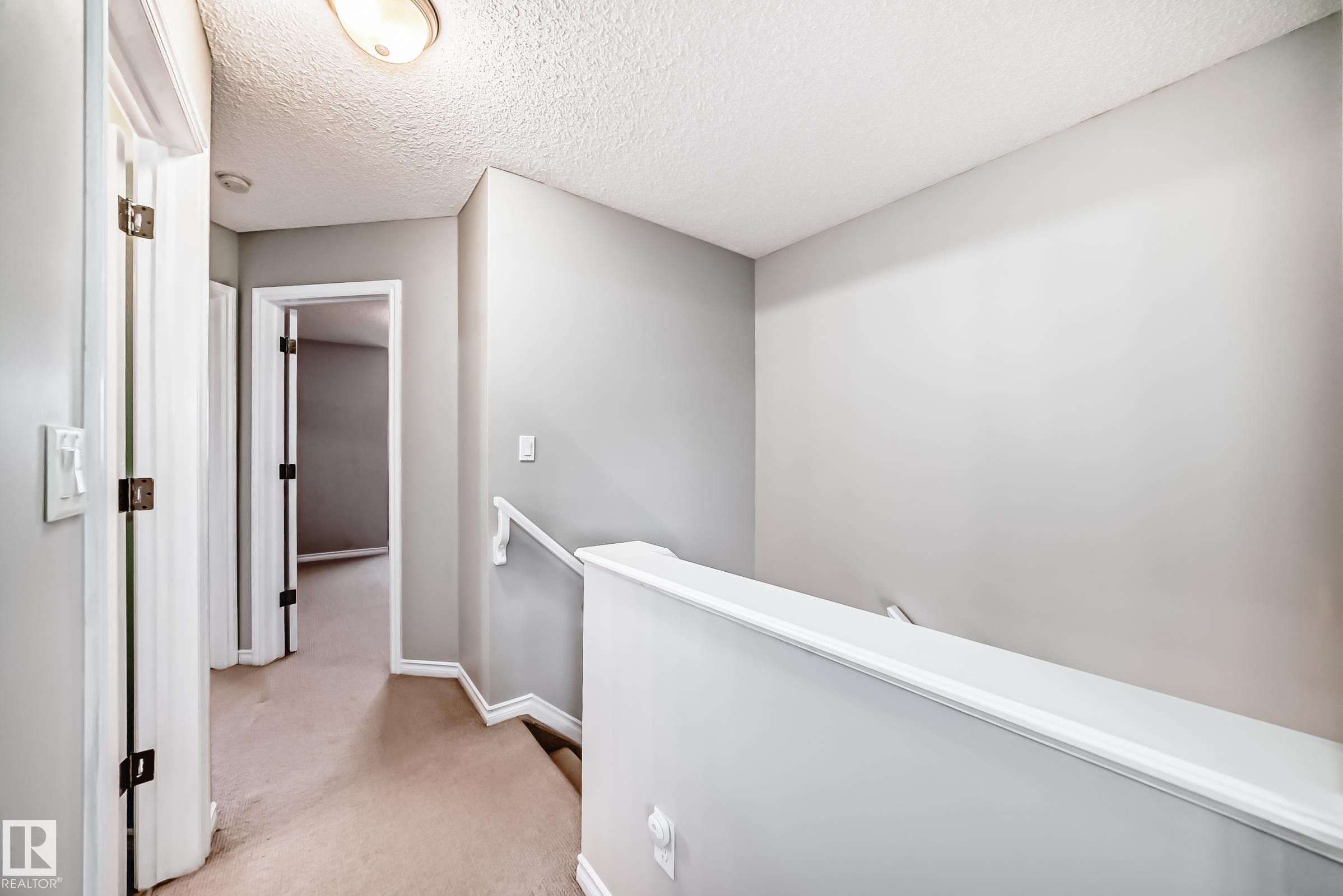 Hallway featuring neutral-toned walls, carpeted flooring, and white trim - 105 13825 155 Avenue, Edmonton, AB - Indoor Photo Showing Other Room