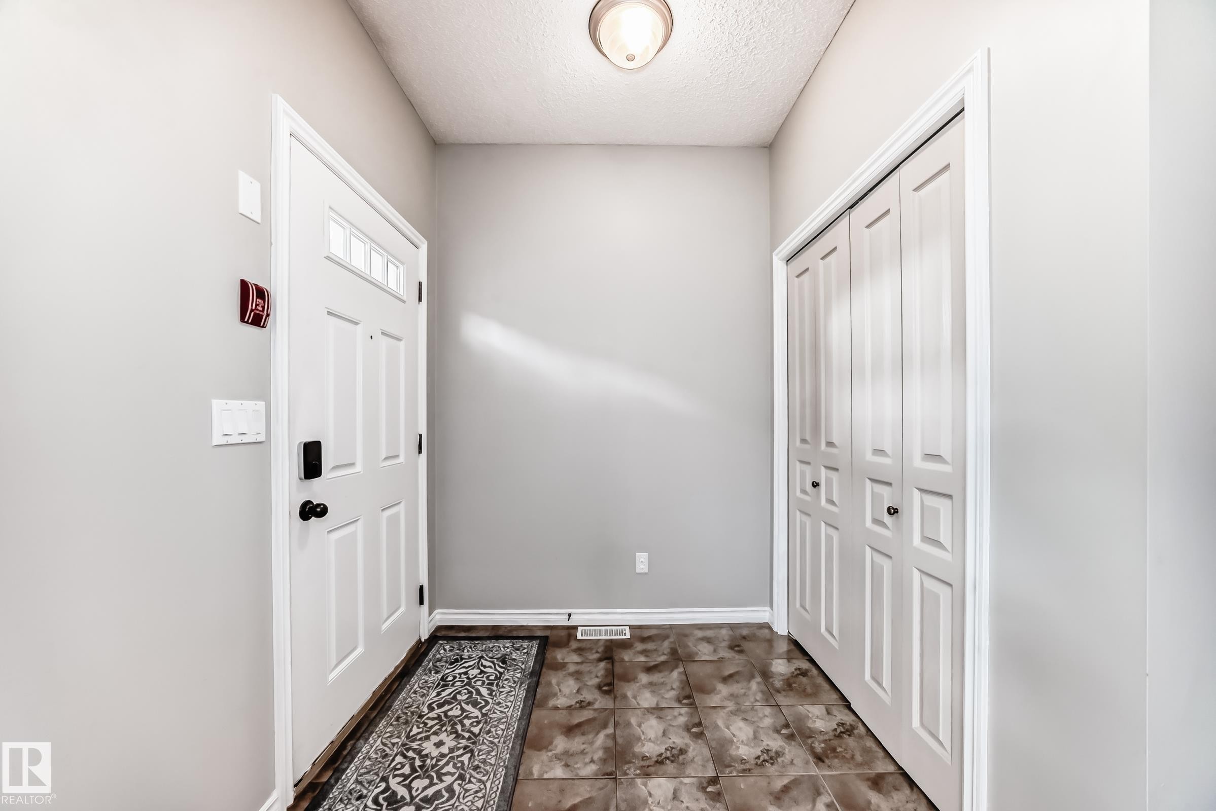 Entryway featuring a white paneled door with transom window, tile flooring, and a flush-mount ceiling light - 105 13825 155 Avenue, Edmonton, AB - Indoor Photo Showing Other Room