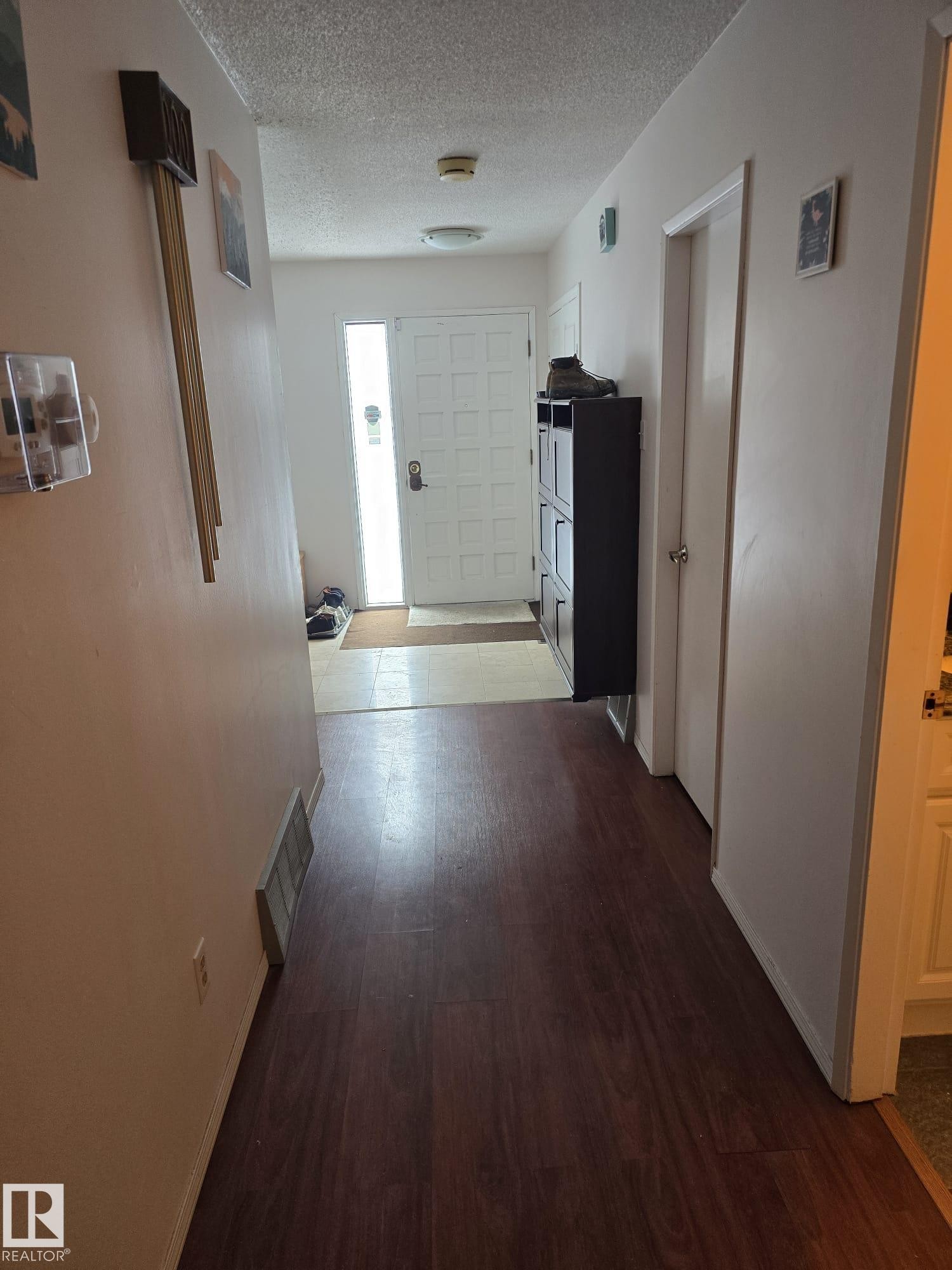 Entryway featuring wood-finish flooring, a paneled front door with a vertical frosted glass insert, and a flush-mount ceiling light - 11927 85 Street Nw, Edmonton, AB - Indoor Photo Showing Other Room