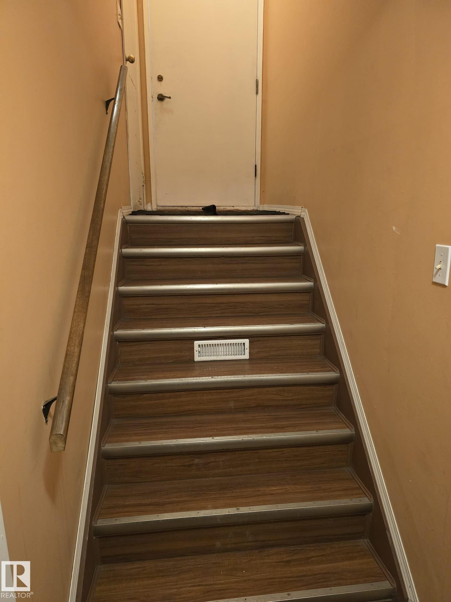 Staircase featuring wood-finish treads with metallic anti-slip strips, a light wood handrail, and a white interior door - 11927 85 Street Nw, Edmonton, AB - Indoor Photo Showing Other Room