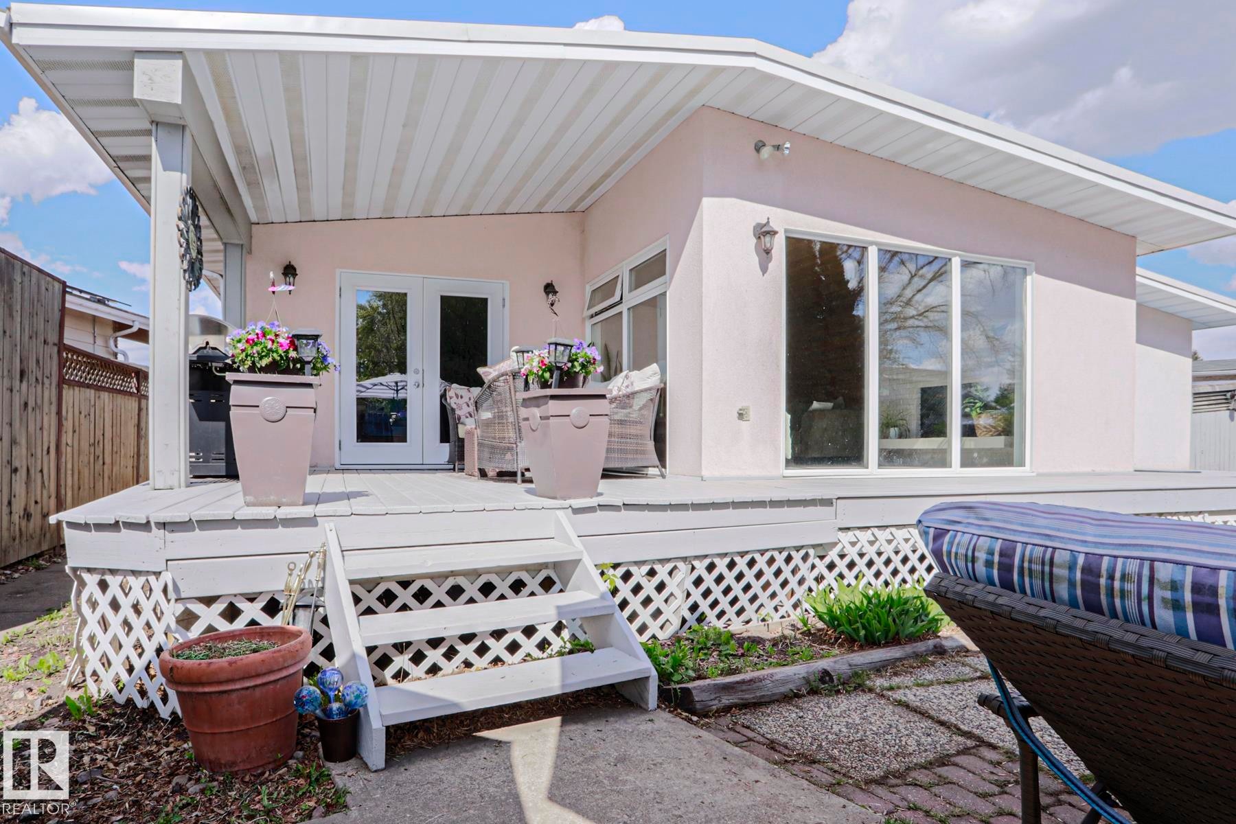 Expansive outdoor deck with a covered patio area, featuring white lattice skirting and painted wood steps - 1214 85 Street Nw, Edmonton, AB - Outdoor With Deck Patio Veranda With Exterior