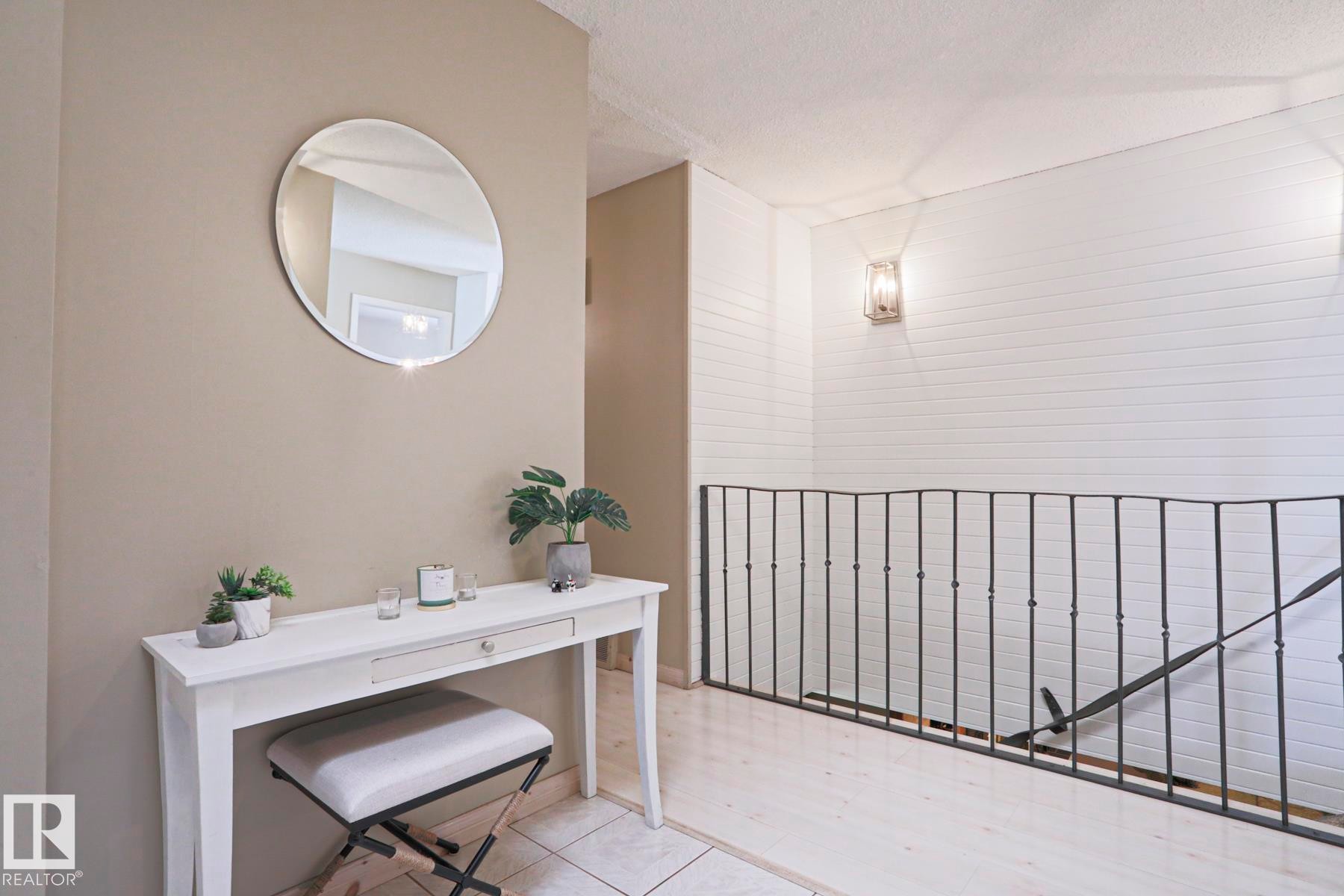 Wrought iron railing defining the stairwell, complemented by vertical shiplap wall paneling and wall sconce lighting - 1214 85 Street Nw, Edmonton, AB - Indoor