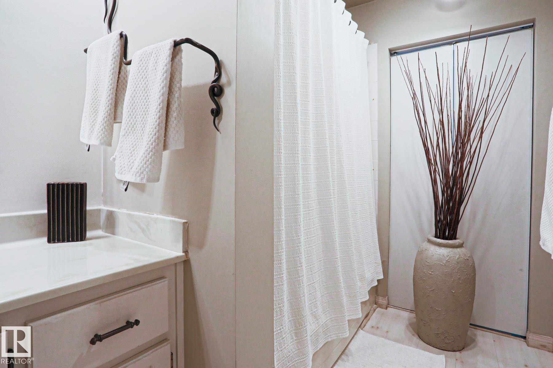 White cabinetry with decorative hardware, a light-colored countertop, and a dark, ornate towel bar - 1214 85 Street Nw, Edmonton, AB - Indoor Photo Showing Bathroom