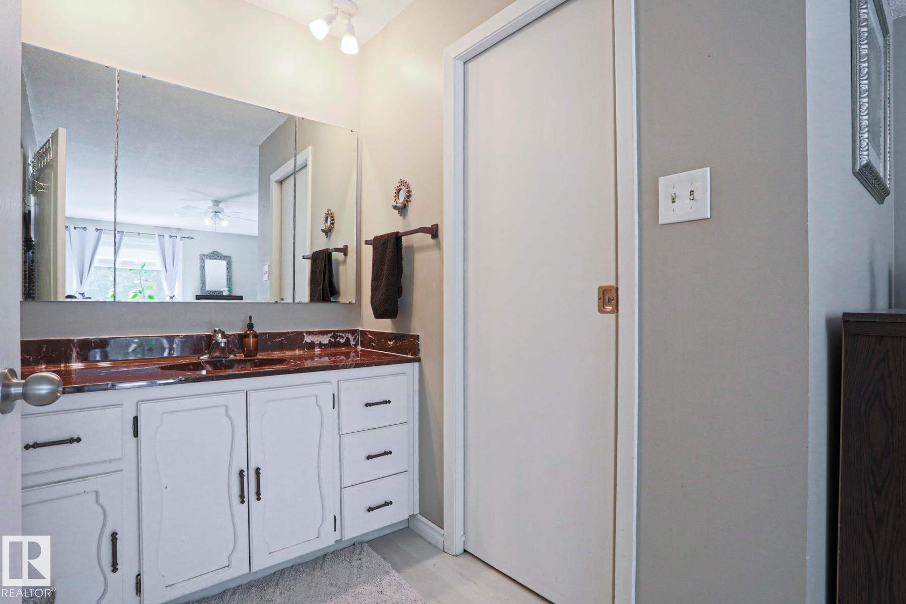 Bathroom vanity featuring a brown countertop, integrated sink, and white cabinetry with dark hardware - 1214 85 Street Nw, Edmonton, AB - Indoor Photo Showing Bathroom