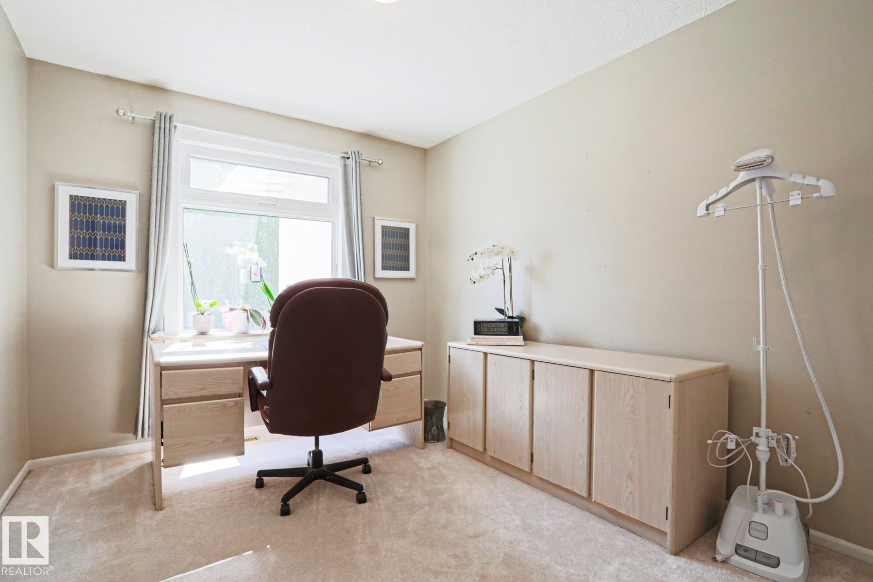 Carpeted room featuring a window with drapes, a built-in desk, and built-in cabinetry - 1214 85 Street Nw, Edmonton, AB - Indoor Photo Showing Office