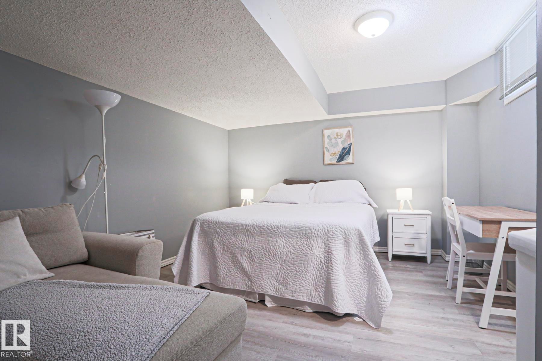 Spacious room featuring wood-finish flooring, light gray walls, and a textured ceiling - 1214 85 Street Nw, Edmonton, AB - Indoor Photo Showing Bedroom