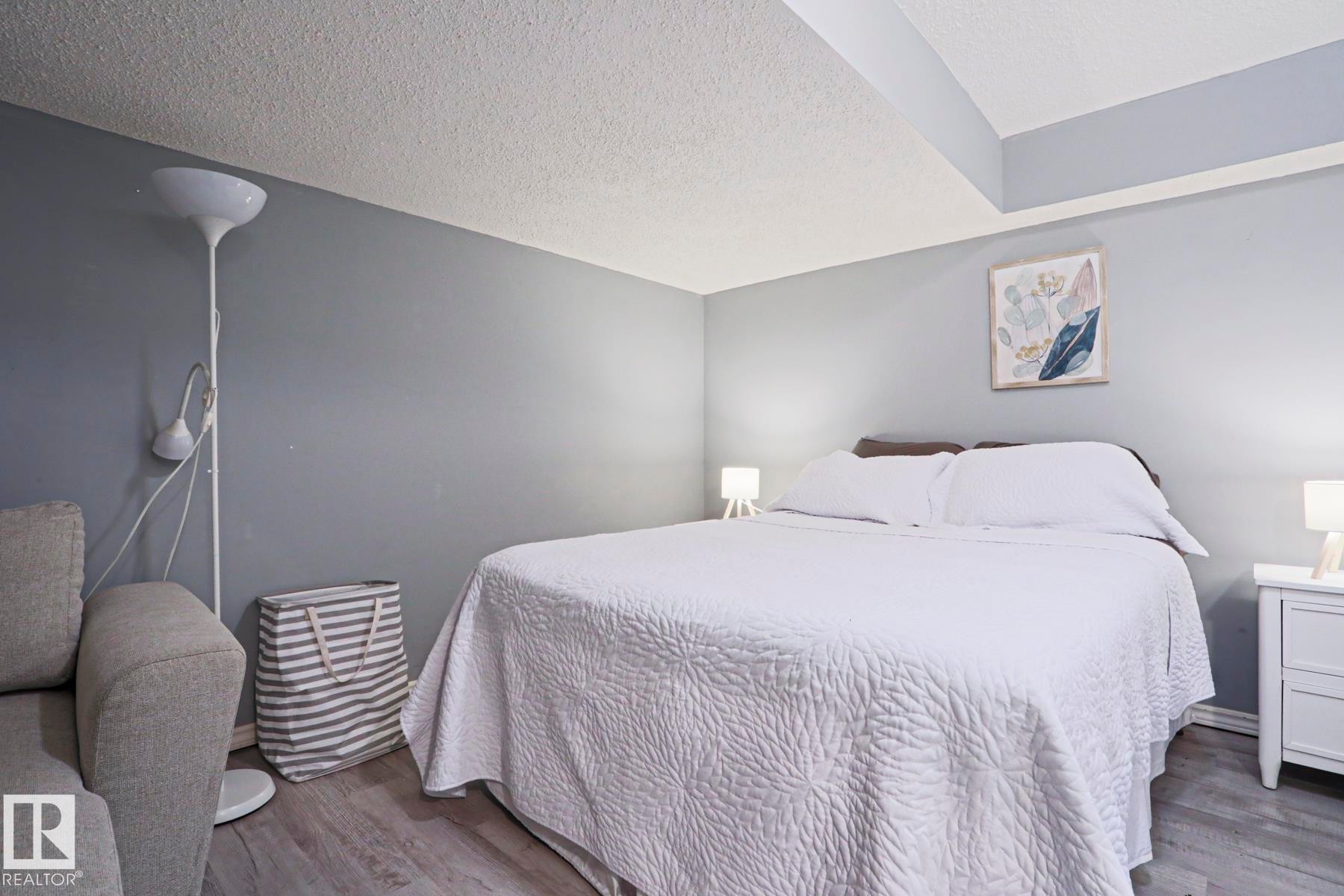 Bedroom featuring light gray walls, wood-finish flooring, and a white nightstand - 1214 85 Street Nw, Edmonton, AB - Indoor Photo Showing Bedroom