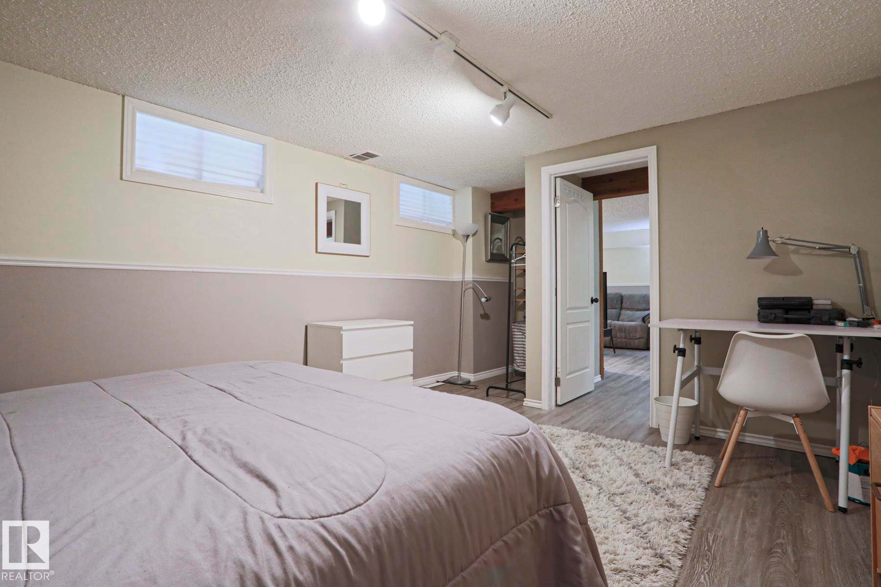 Finished room featuring wood-finish flooring, two-tone wall paint with wainscoting, and recessed windows - 1214 85 Street Nw, Edmonton, AB - Indoor Photo Showing Bedroom