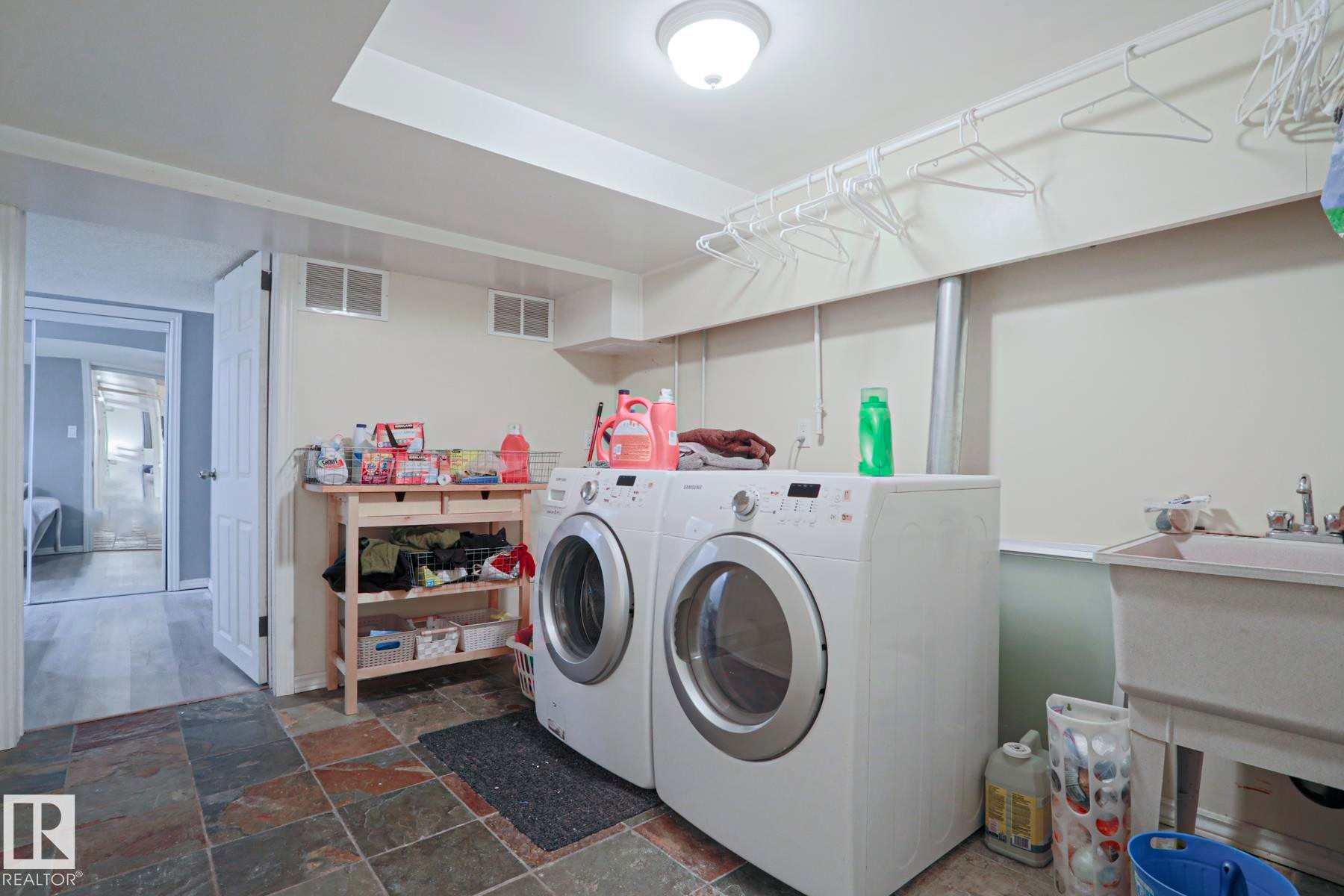 Functional utility room featuring slate tile flooring, a utility sink, and overhead lighting - 1214 85 Street Nw, Edmonton, AB - Indoor Photo Showing Laundry Room