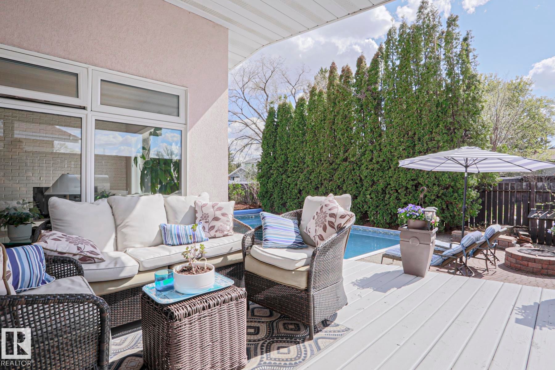 Expansive outdoor deck area featuring a built-in swimming pool and a brick fire pit - 1214 85 Street Nw, Edmonton, AB - Outdoor With Deck Patio Veranda With Exterior