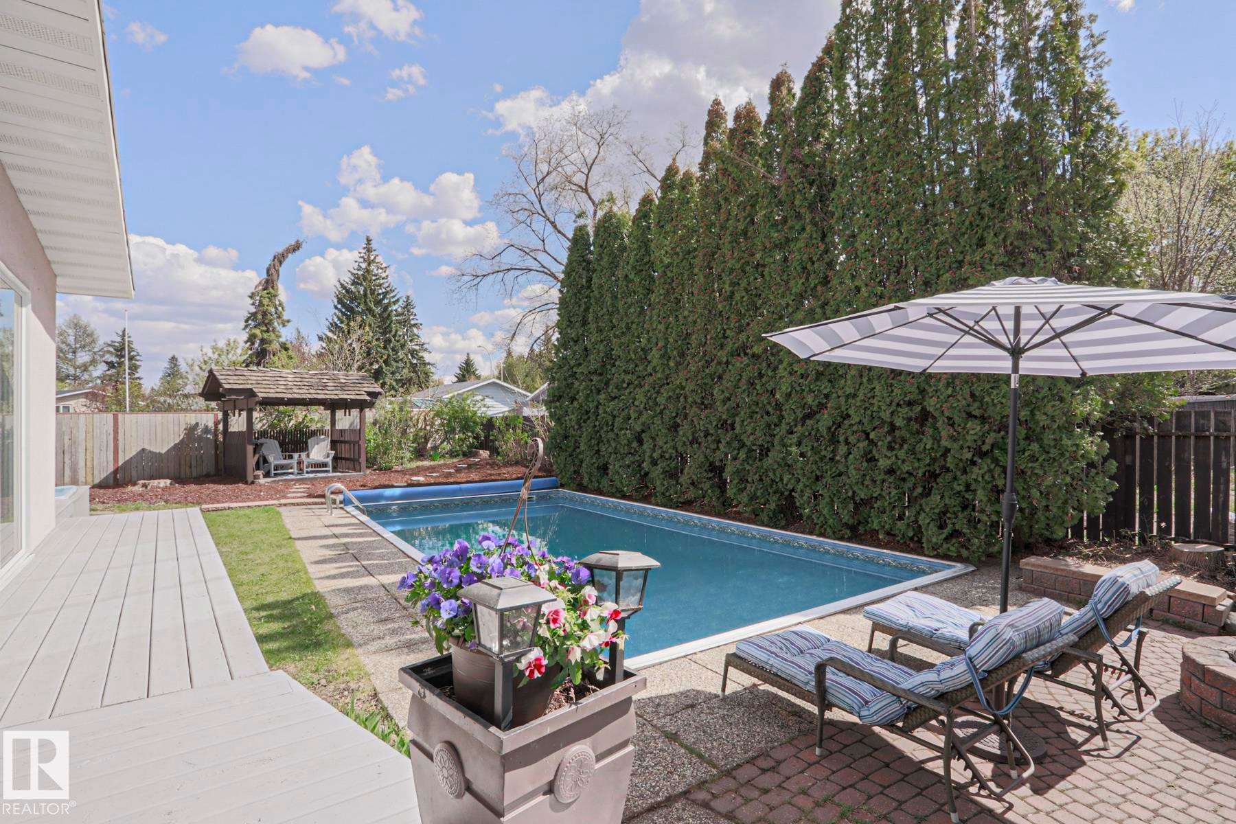 Outdoor swimming pool with a surrounding brick patio and wood-finish deck - 1214 85 Street Nw, Edmonton, AB - Outdoor With In Ground Pool With Deck Patio Veranda With Backyard