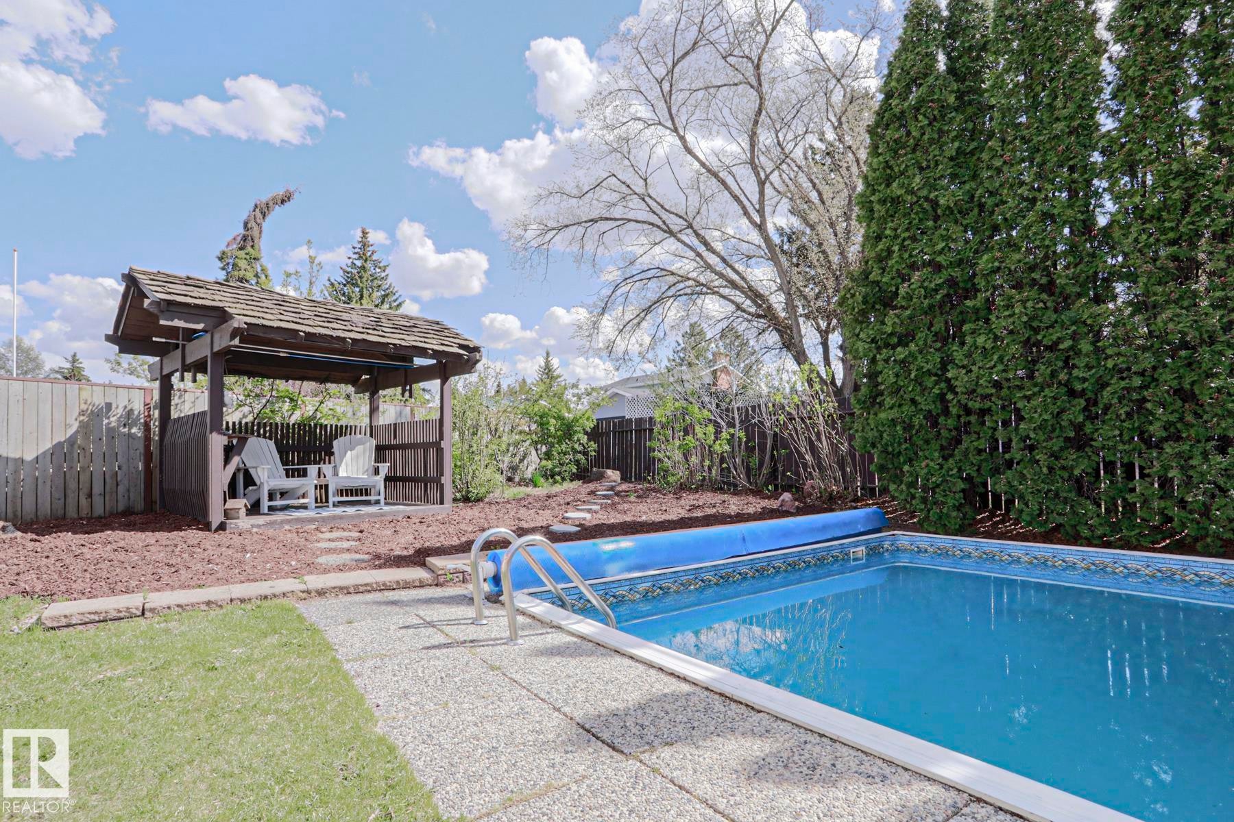 Outdoor swimming pool with integrated steps, surrounded by a textured concrete deck - 1214 85 Street Nw, Edmonton, AB - Outdoor With In Ground Pool With Backyard