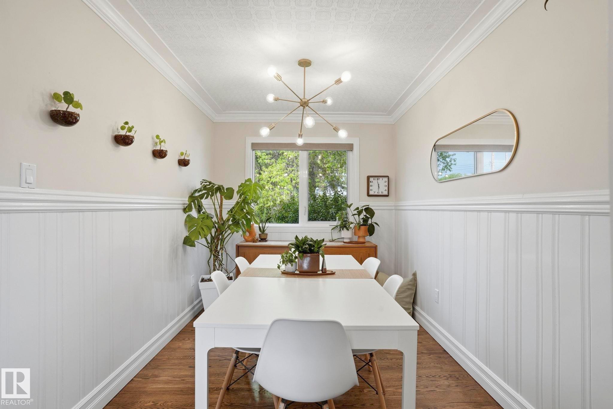 Dining space featuring wainscoting, crown molding, wood-finish flooring, and a modern sputnik chandelier - 4 Langley Dr, Fort Saskatchewan, AB - Indoor Photo Showing Dining Room