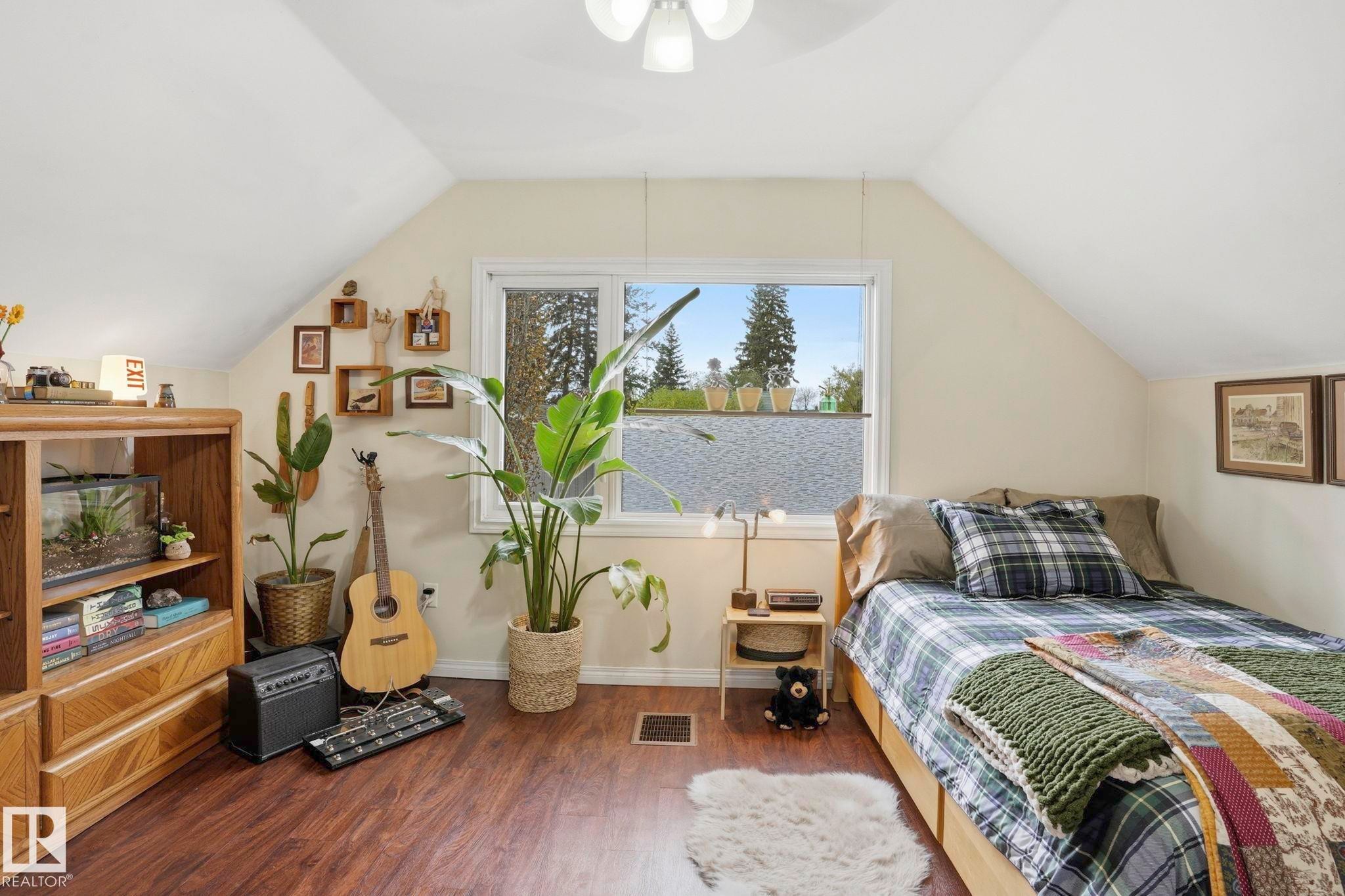 Attic room featuring sloped ceilings, a bright window, wood-finish flooring, and a built-in storage unit - 4 Langley Dr, Fort Saskatchewan, AB - Indoor Photo Showing Bedroom