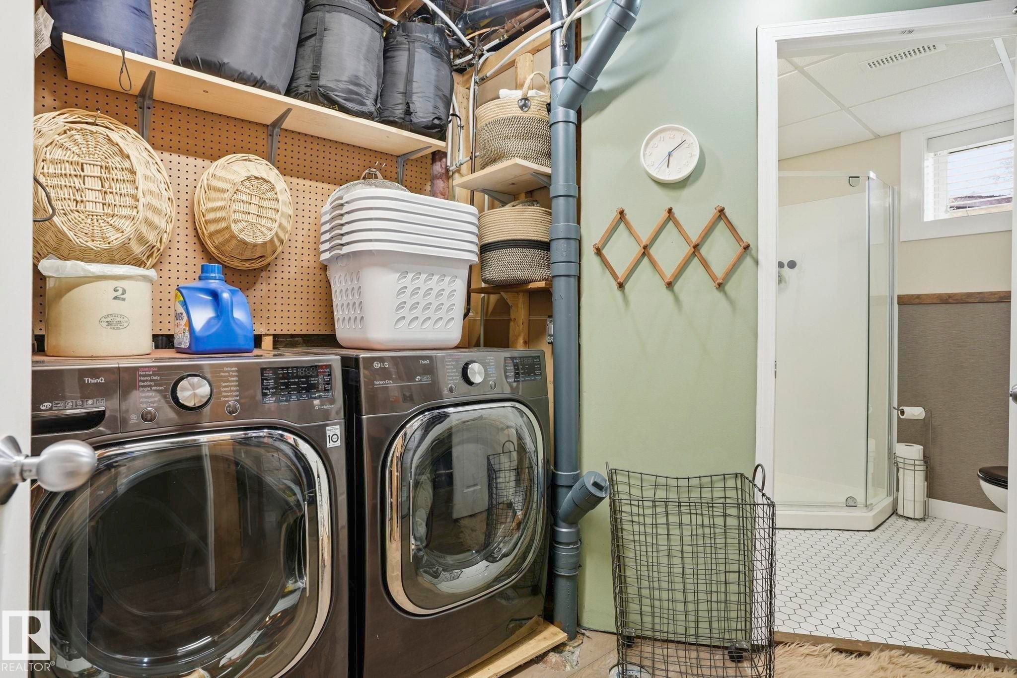 Dedicated laundry area featuring front-loading washer and dryer, adjacent to a bathroom with a shower enclosure - 4 Langley Dr, Fort Saskatchewan, AB - Indoor Photo Showing Laundry Room