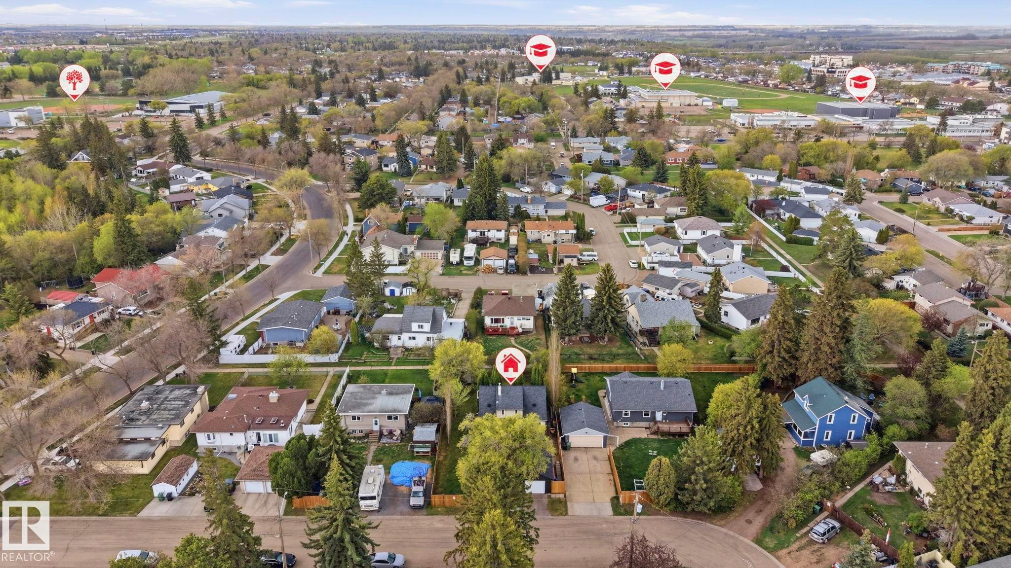 Aerial perspective showcasing a residential neighborhood with established trees, paved streets, and a mix of single-family homes - 4 Langley Dr, Fort Saskatchewan, AB - Outdoor With View