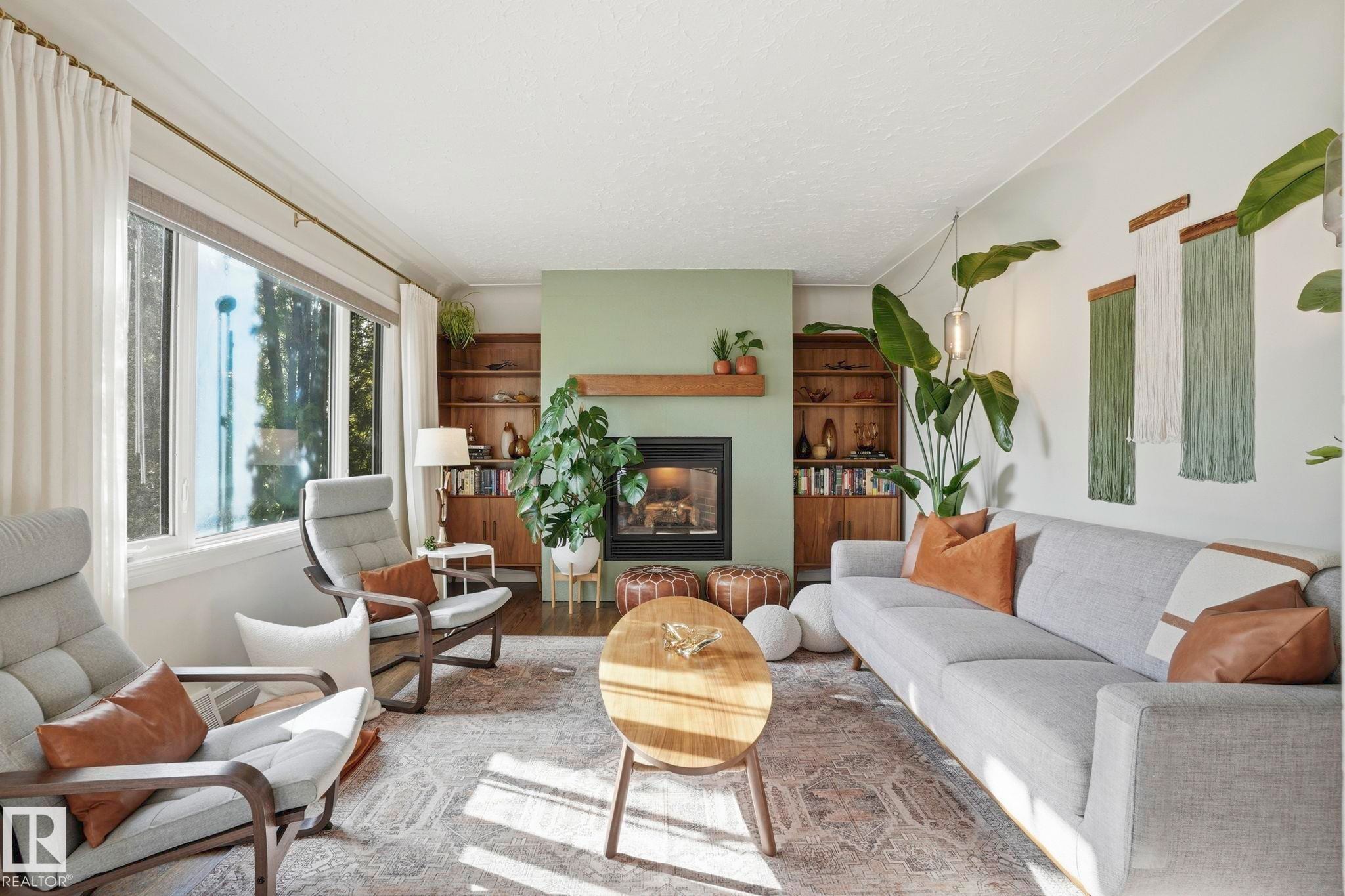 Living area featuring a fireplace with a wood mantle, built-in shelving, large window, and light-toned walls - 4 Langley Dr, Fort Saskatchewan, AB - Indoor Photo Showing Living Room With Fireplace