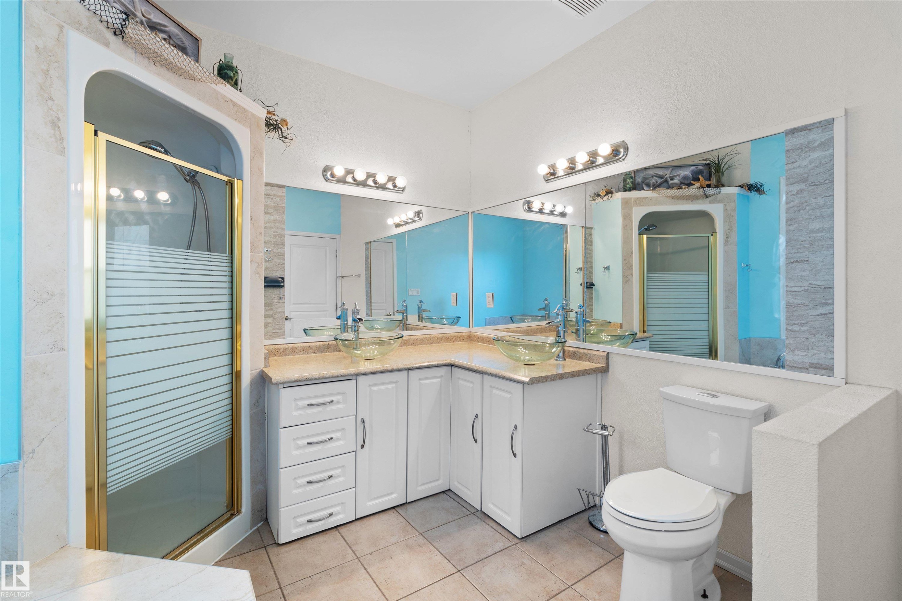 Bathroom featuring a corner vanity with dual vessel sinks, white cabinetry, and a light-toned countertop - 205 10939 82 Avenue, Edmonton, AB - Indoor Photo Showing Bathroom