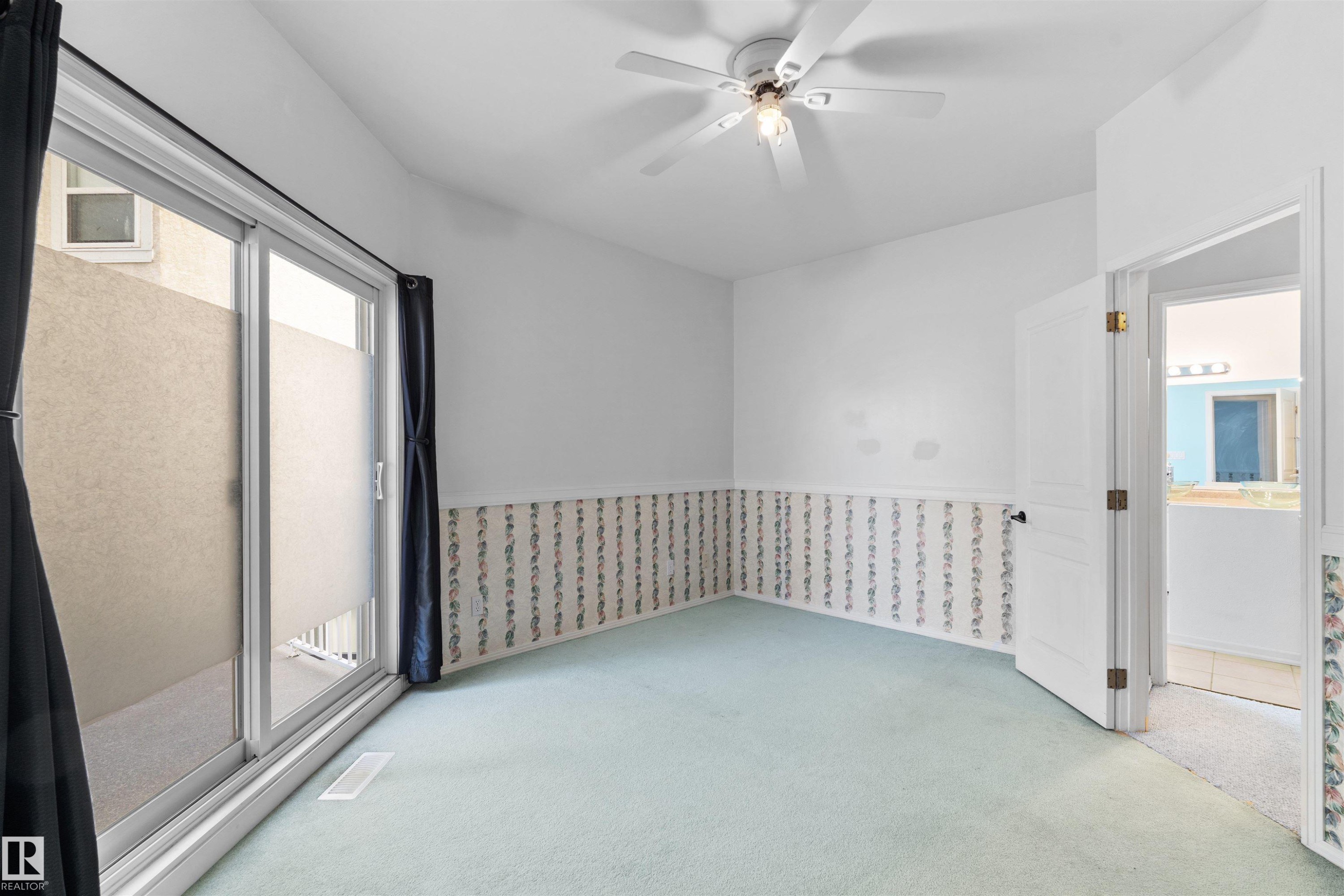 Bright room featuring light blue carpet, a white ceiling fan with integrated lighting, and a sliding glass door providing exterior access - 205 10939 82 Avenue, Edmonton, AB - Indoor Photo Showing Other Room