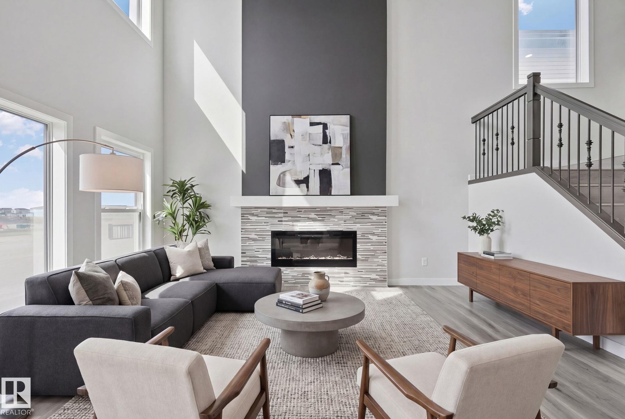 Living area with a two-story ceiling, a fireplace with a stacked stone surround, and a dark accent wall - 334 Aston Close, Leduc, AB - Indoor Photo Showing Living Room With Fireplace