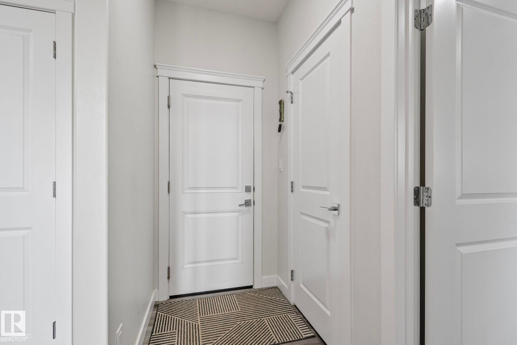Entryway featuring white paneled doors, chrome hardware, and dark wood-finish flooring - 334 Aston Close, Leduc, AB - Indoor Photo Showing Other Room