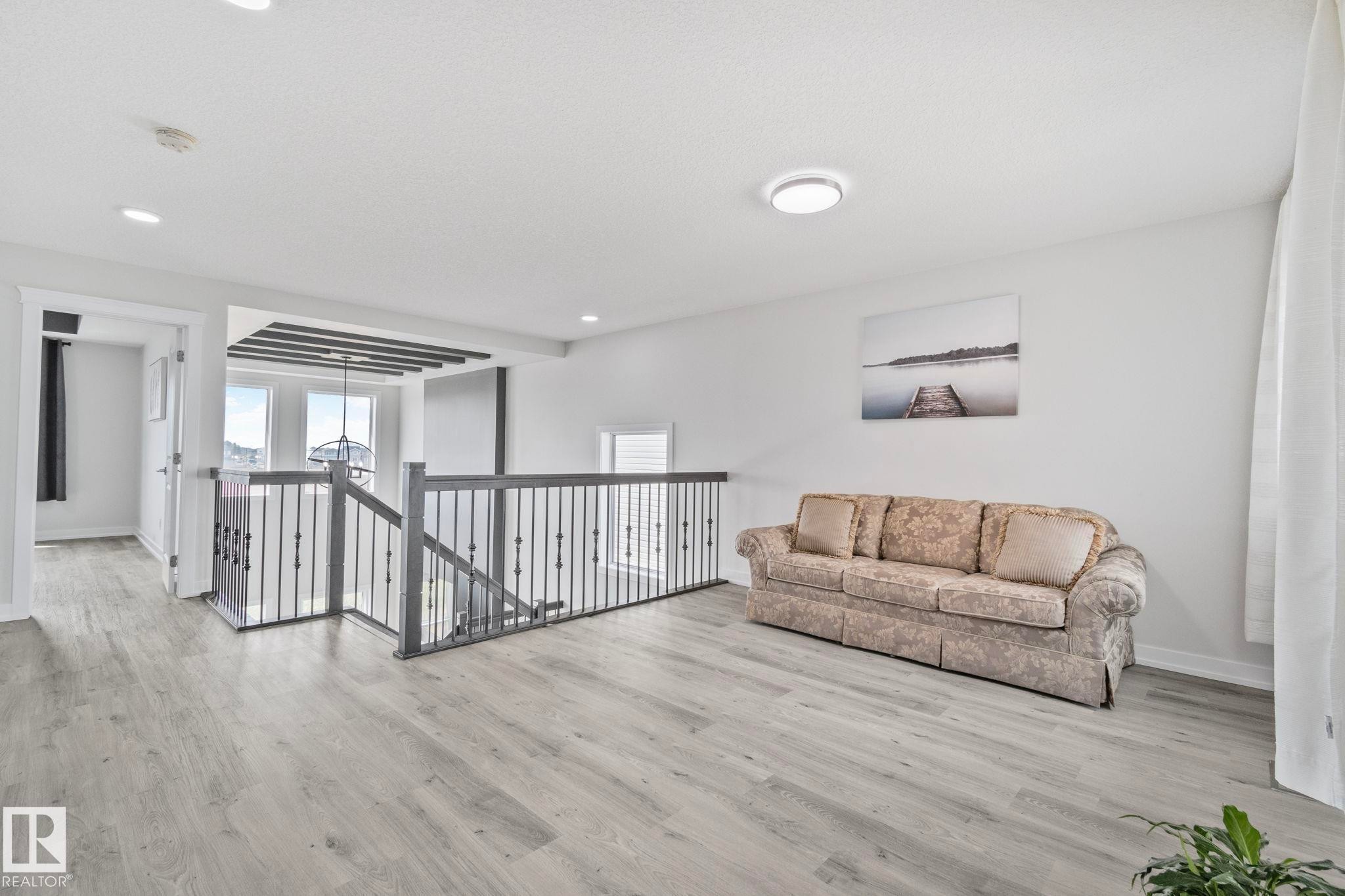 Upper-level landing featuring wood-finish flooring, light gray walls, white trim, and a contemporary ceiling light fixture - 334 Aston Close, Leduc, AB - Indoor