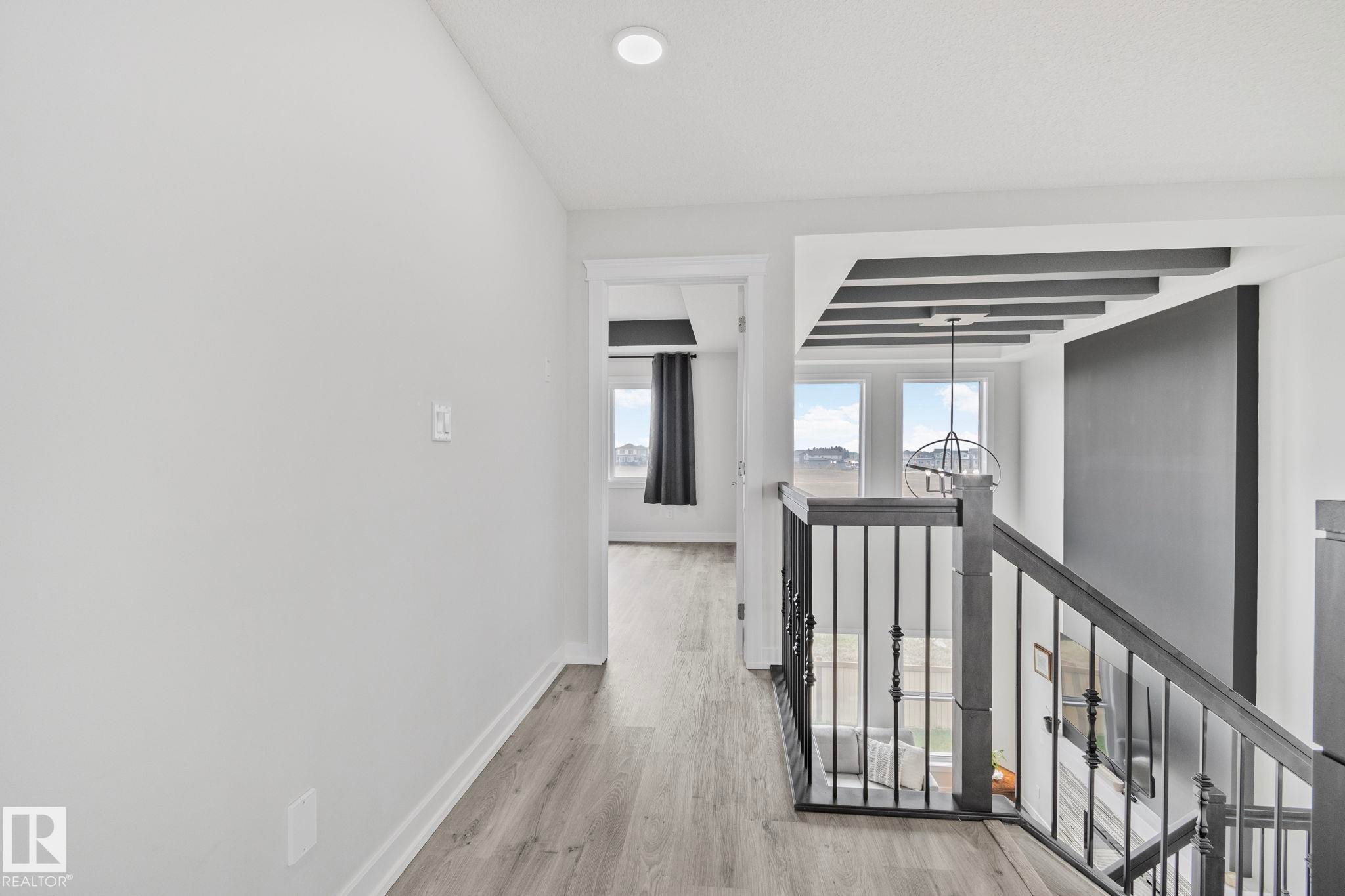 Upper-level hallway featuring wood-finish flooring, recessed lighting, and a doorway leading to an additional space - 334 Aston Close, Leduc, AB - Indoor Photo Showing Other Room